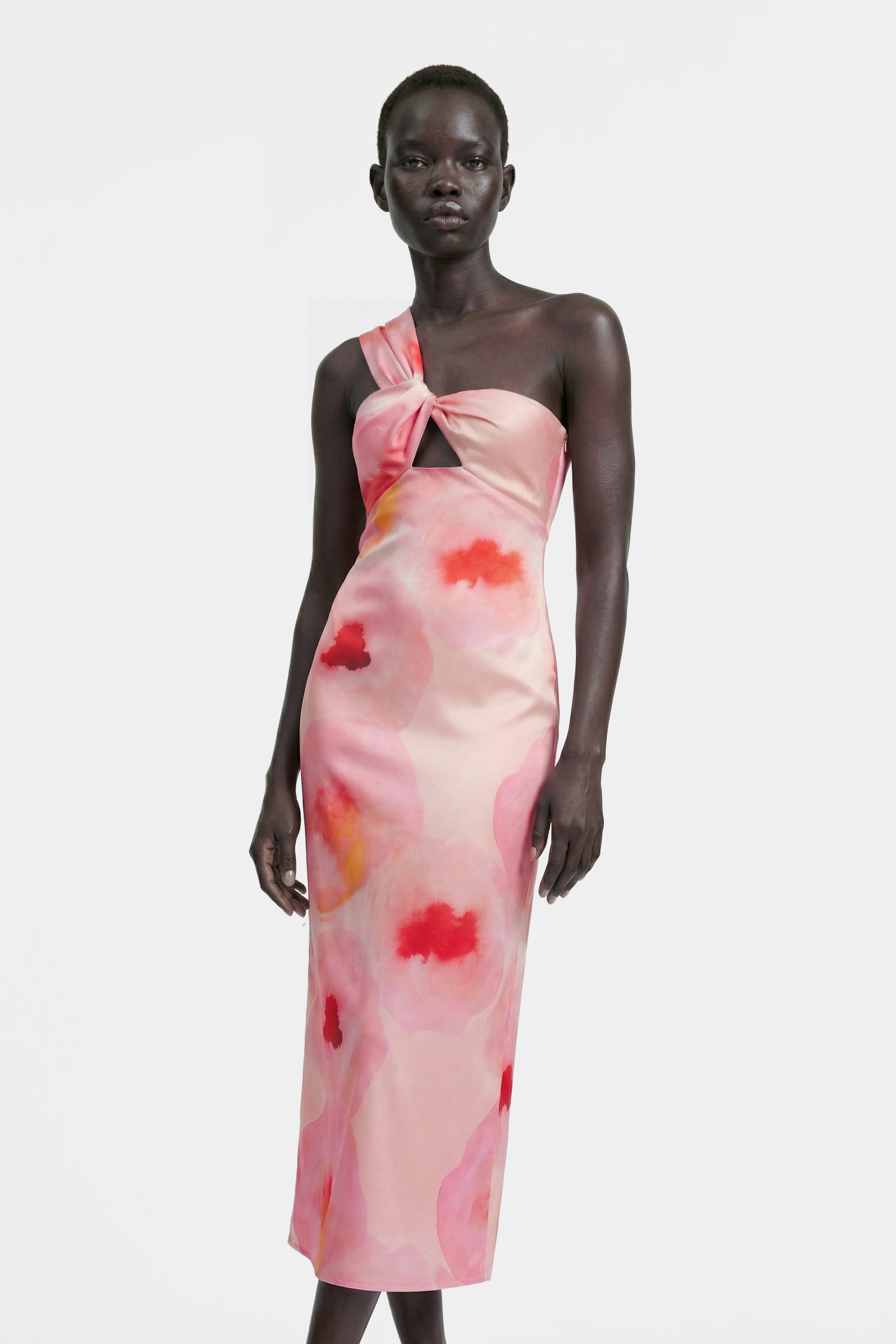 Front view of watercolor one-shoulder dress with knot detail and vibrant pink hues.