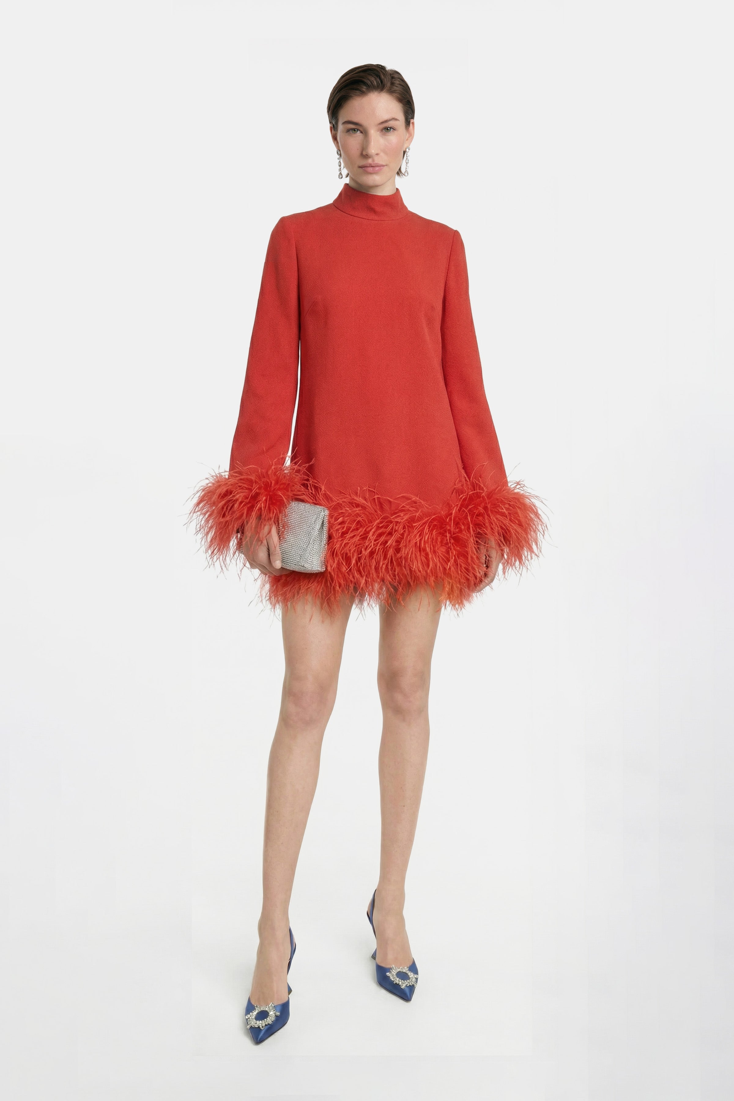Front view of model wearing a red dress with feather trim, blue heels.