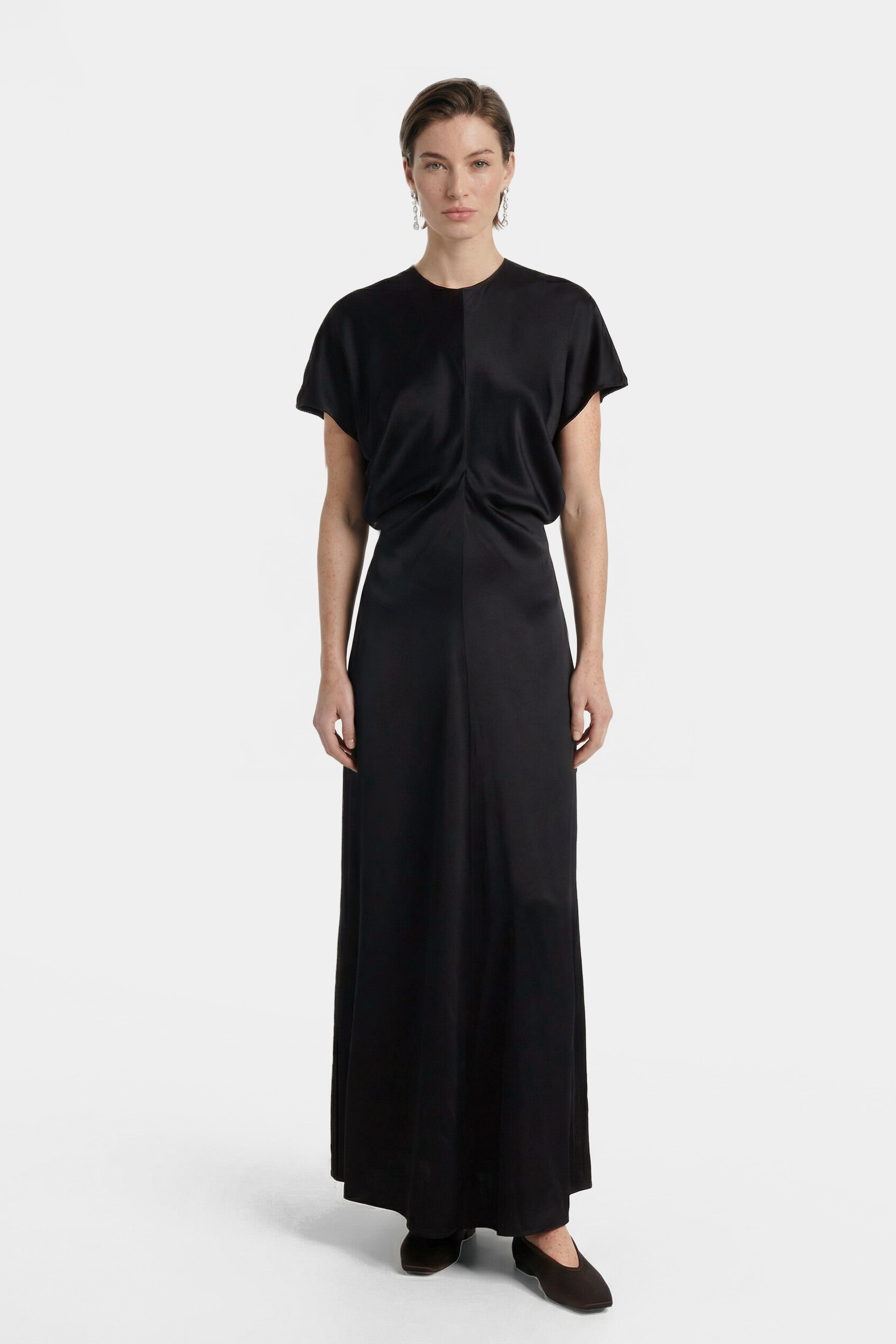 Model wearing a sleek black maxi dress, front view, minimalist design.