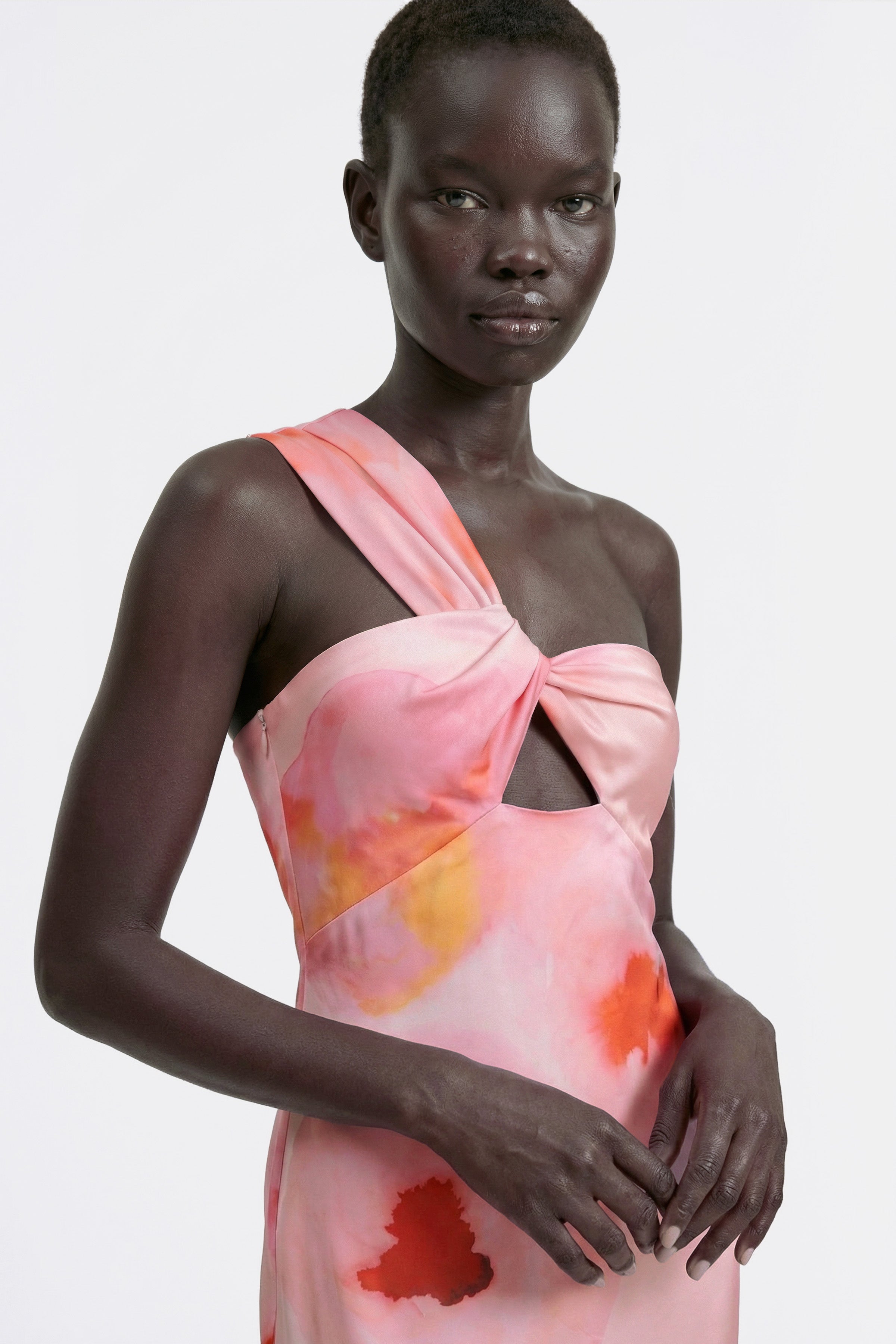 Watercolor one-shoulder dress with knot detail, worn by model, front view.