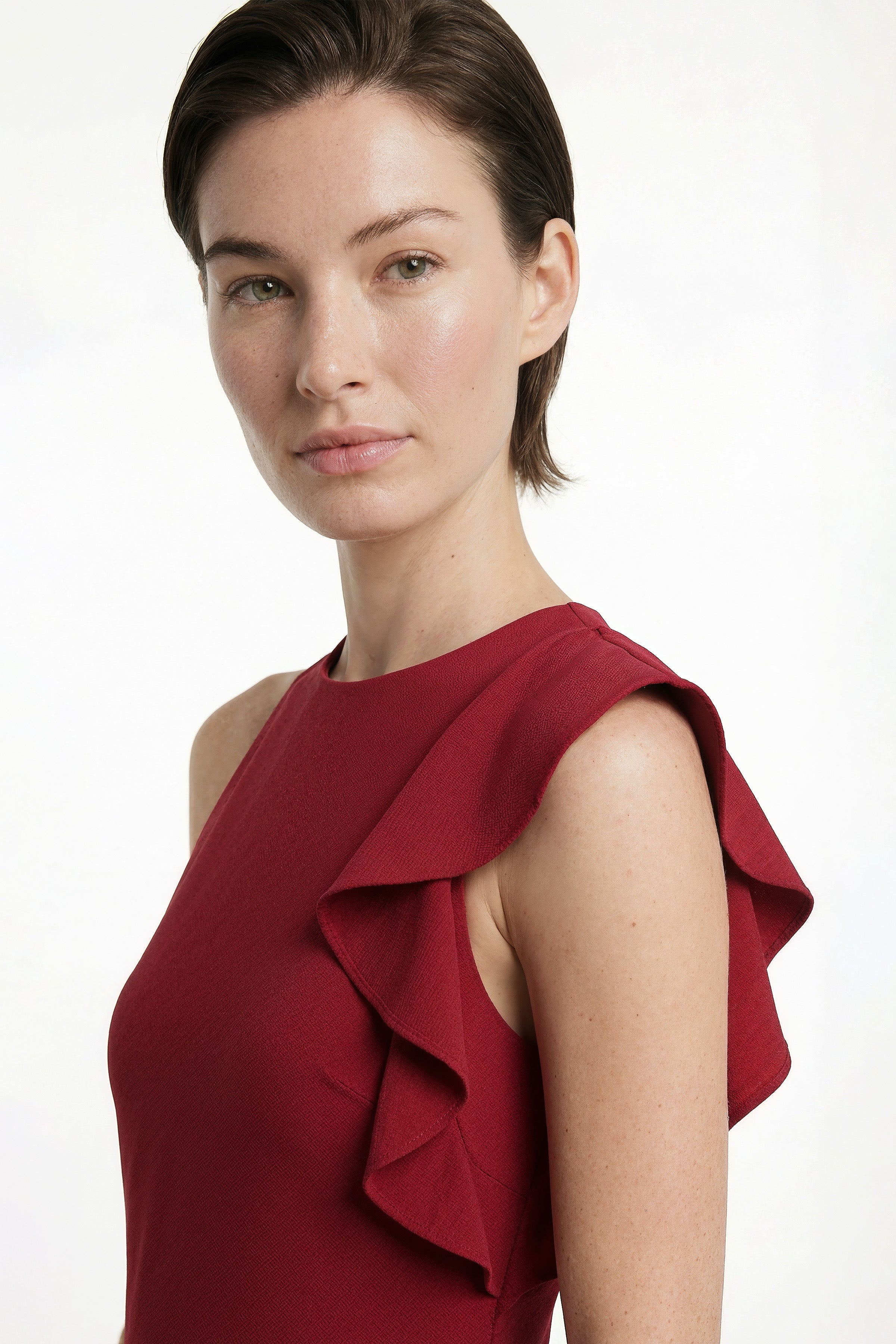 Front view, model in ruffled scarlet mini dress with elegant shoulder detail.