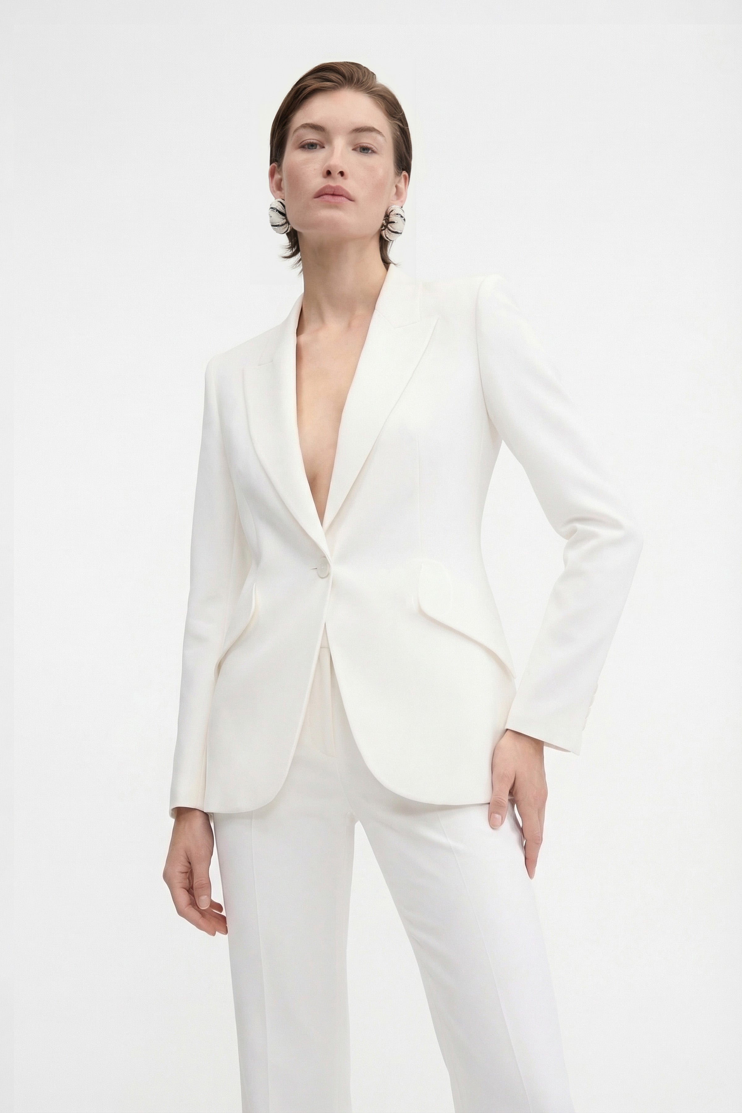Front view of model wearing ivory tailored blazer, single-button closure.