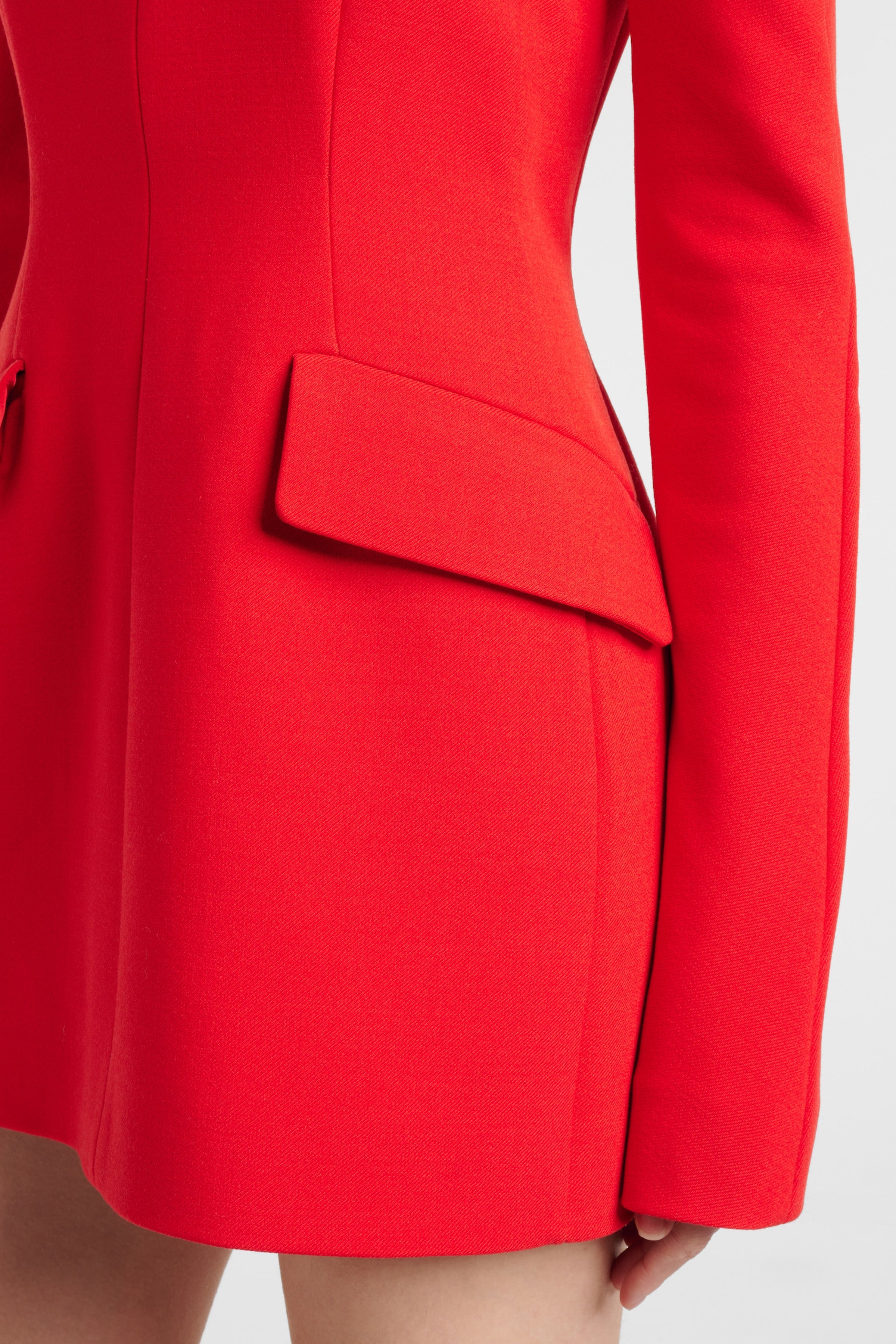 Close-up of a red structured mini dress with a pocket flap detail.