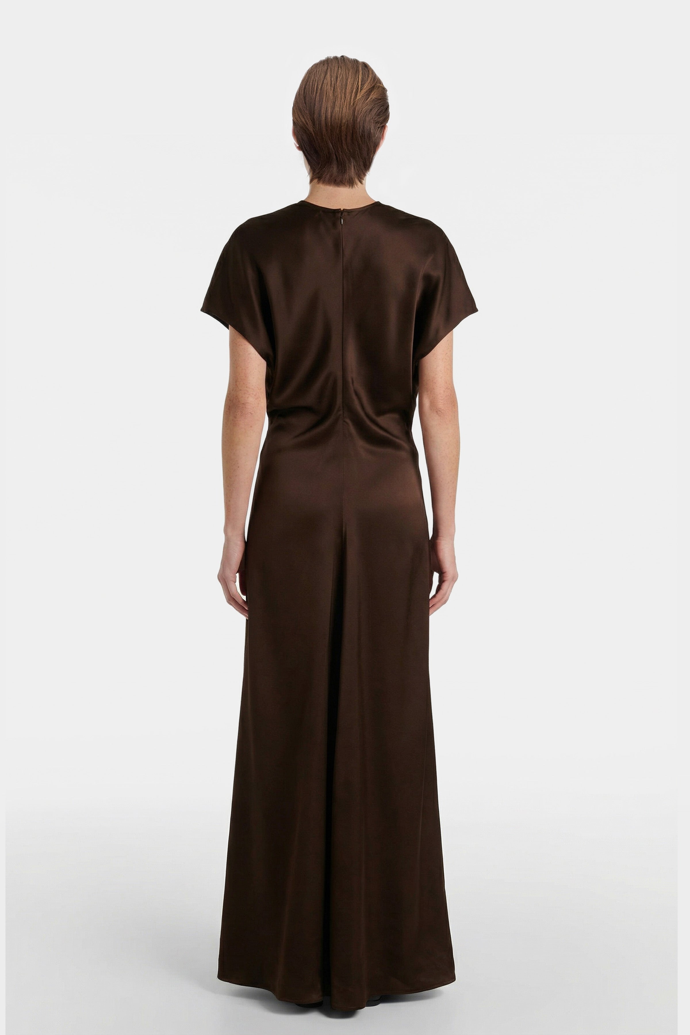 Back view of chocolate satin maxi dress with short sleeves, worn by model.