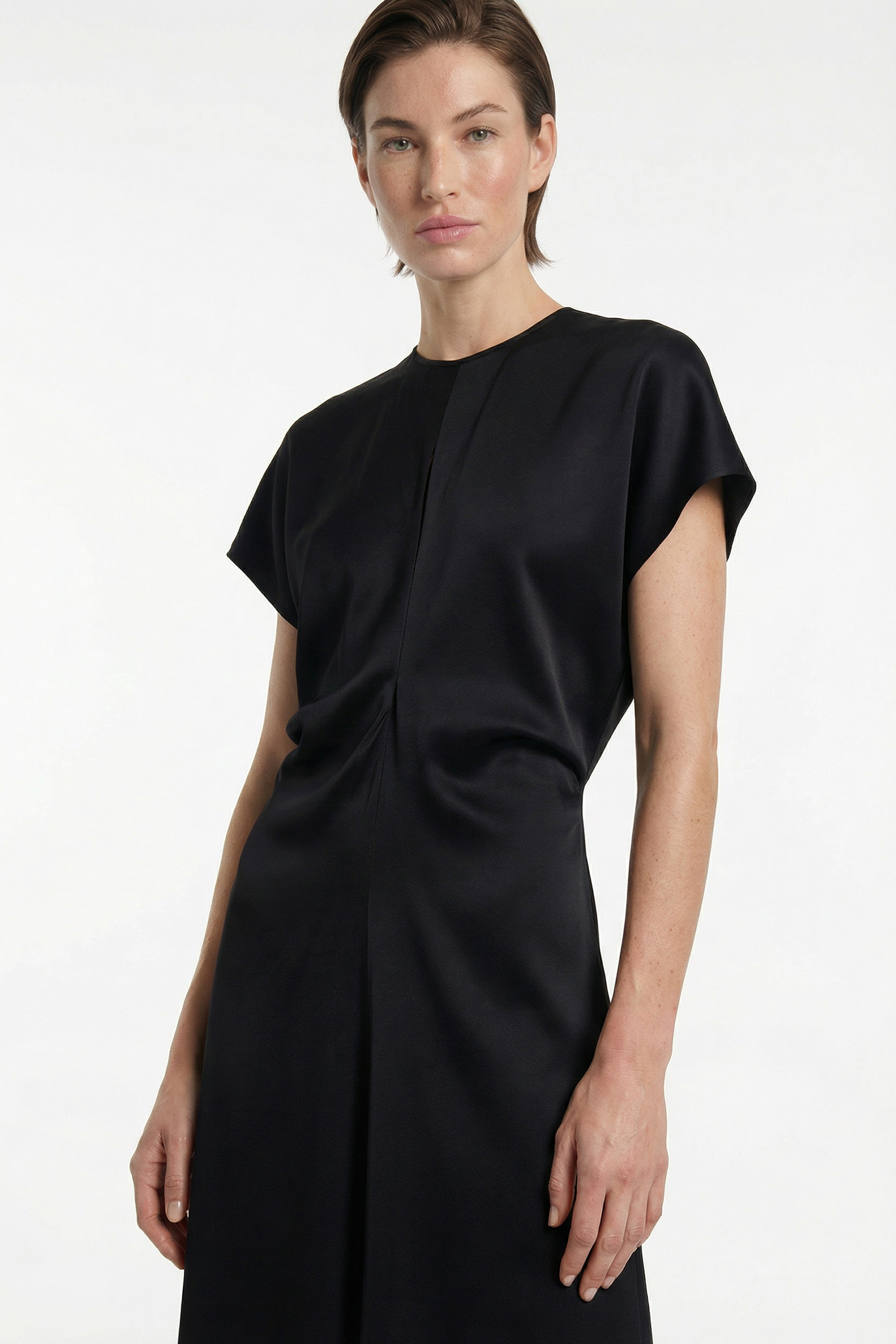 Front view of sleek black maxi dress with cap sleeves, model standing confidently.