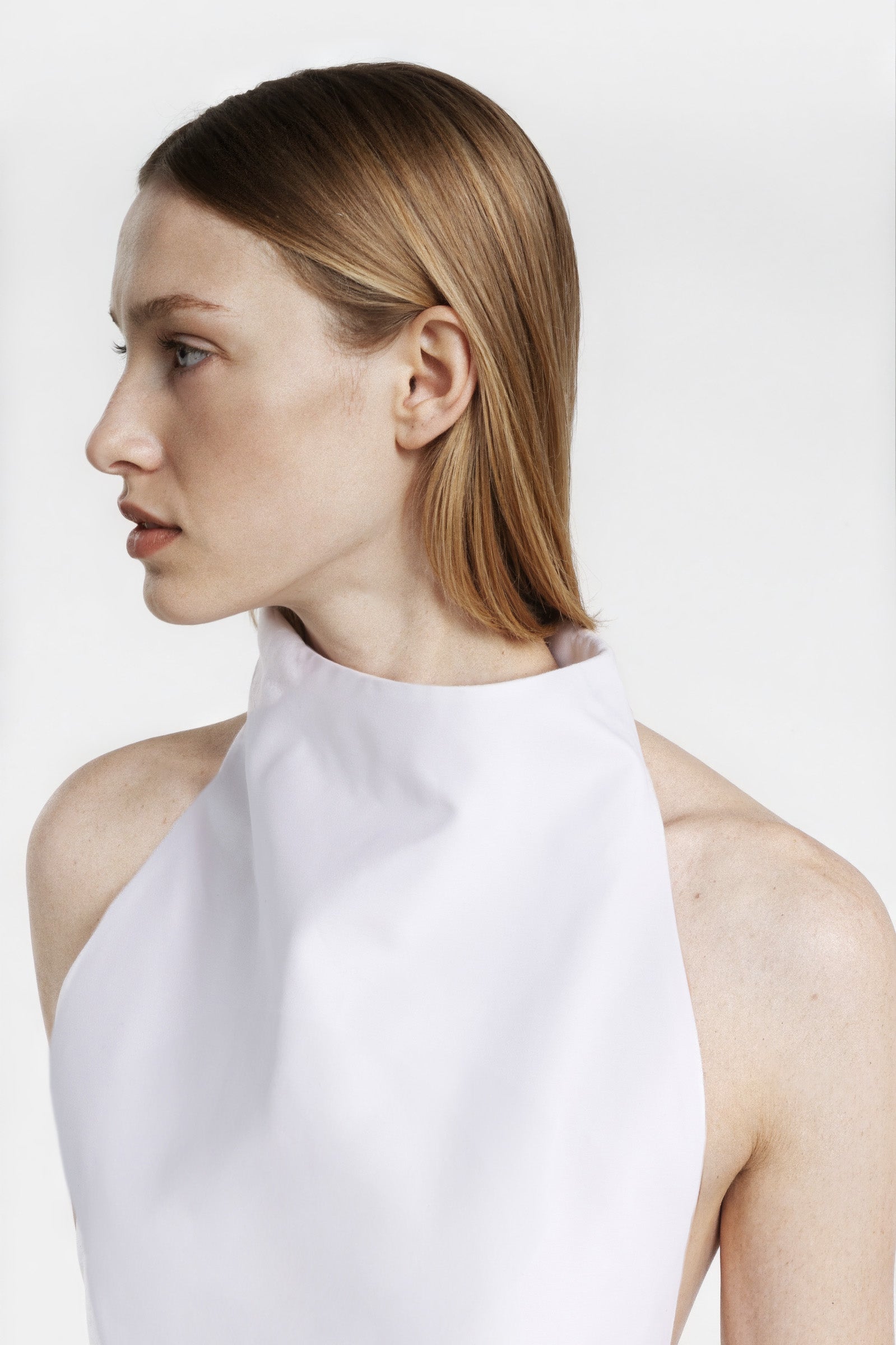 Close-up of the open-back detail and structured hem of a white halter top.