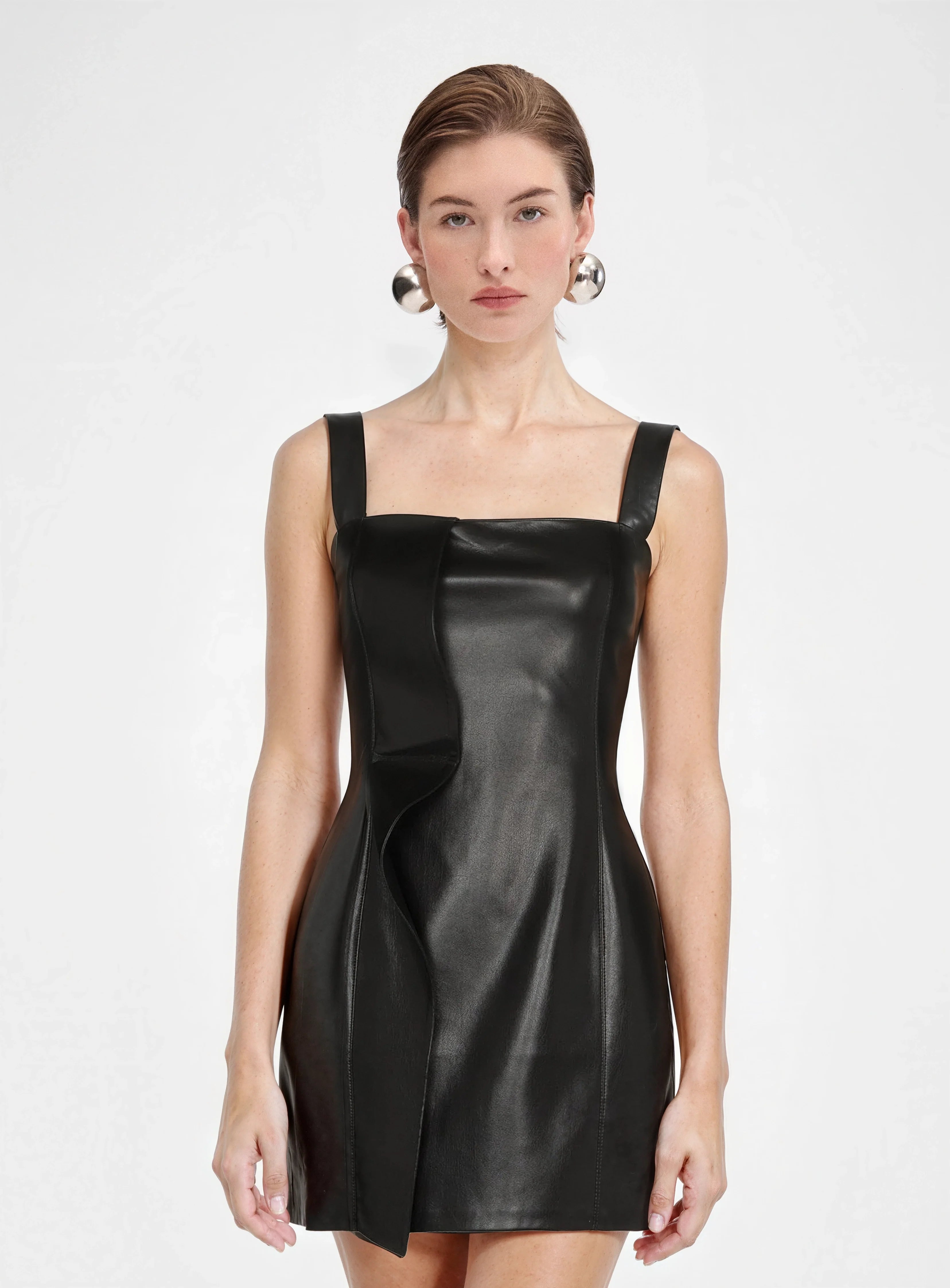 Model wearing black leather mini dress with bold ruffle detail