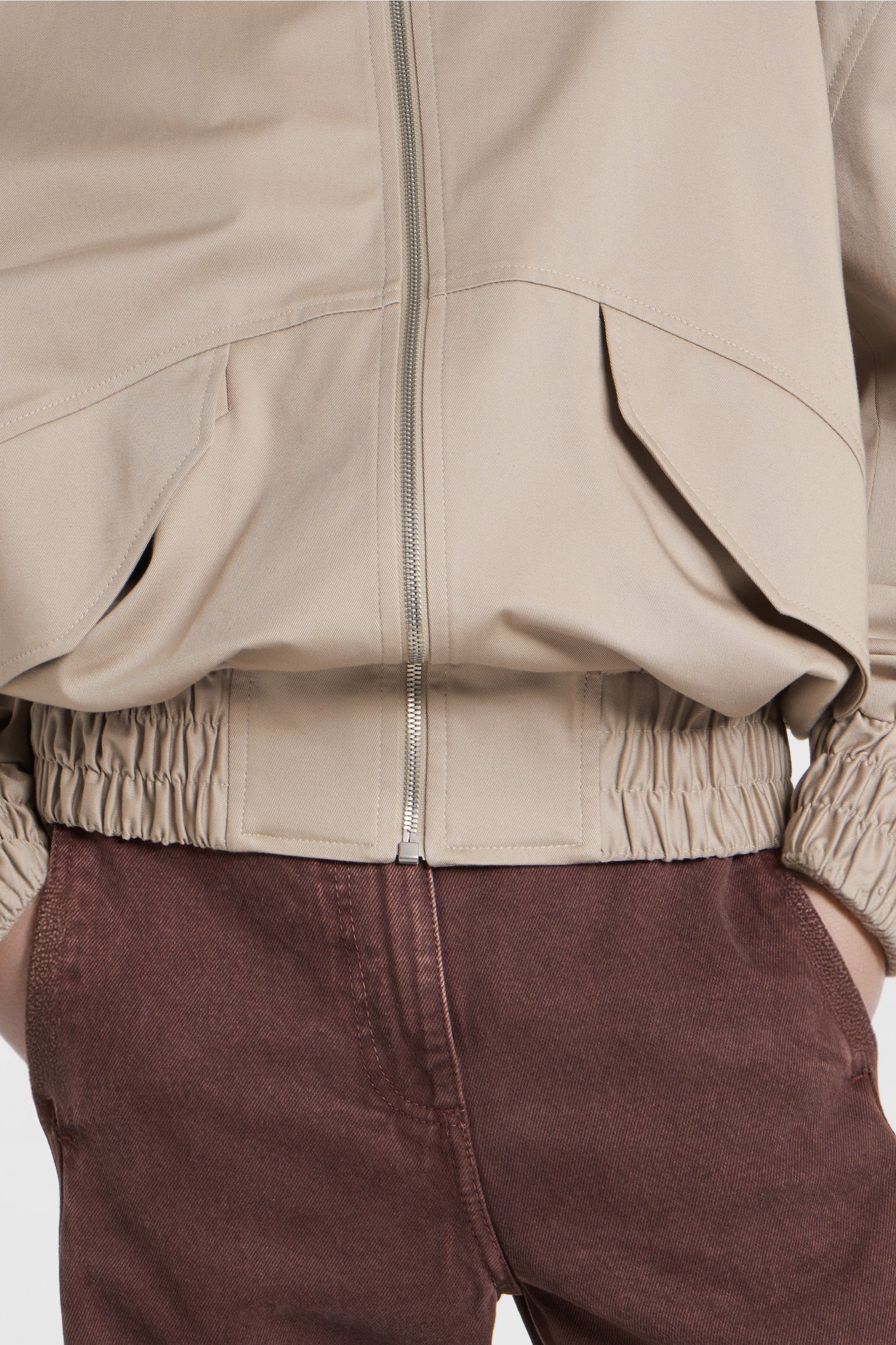 Close-up of high collar with button fastening on beige bomber jacket