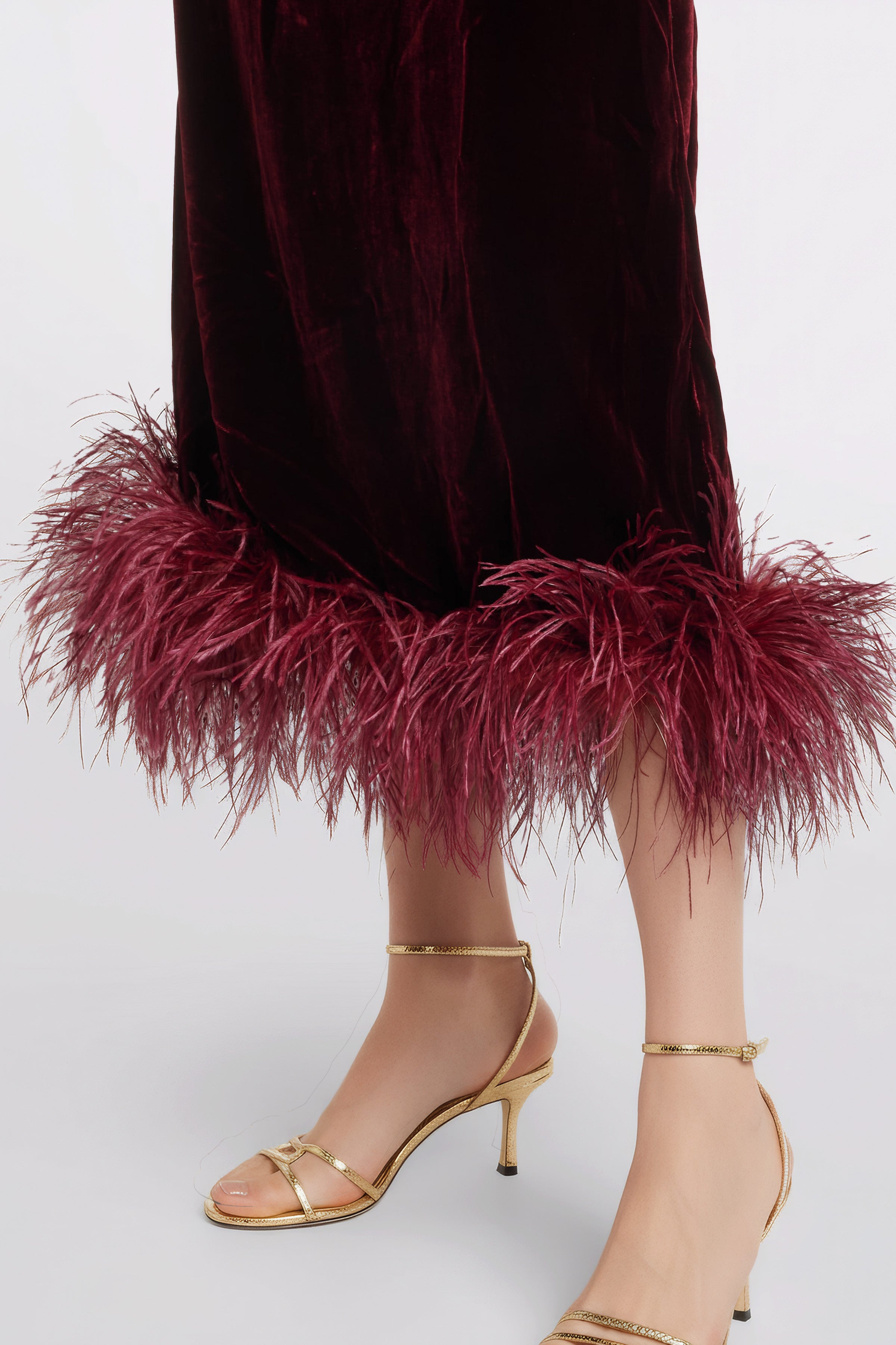 Close-up detail of natural ostrich feathers and wine-colored recycled velvet texture