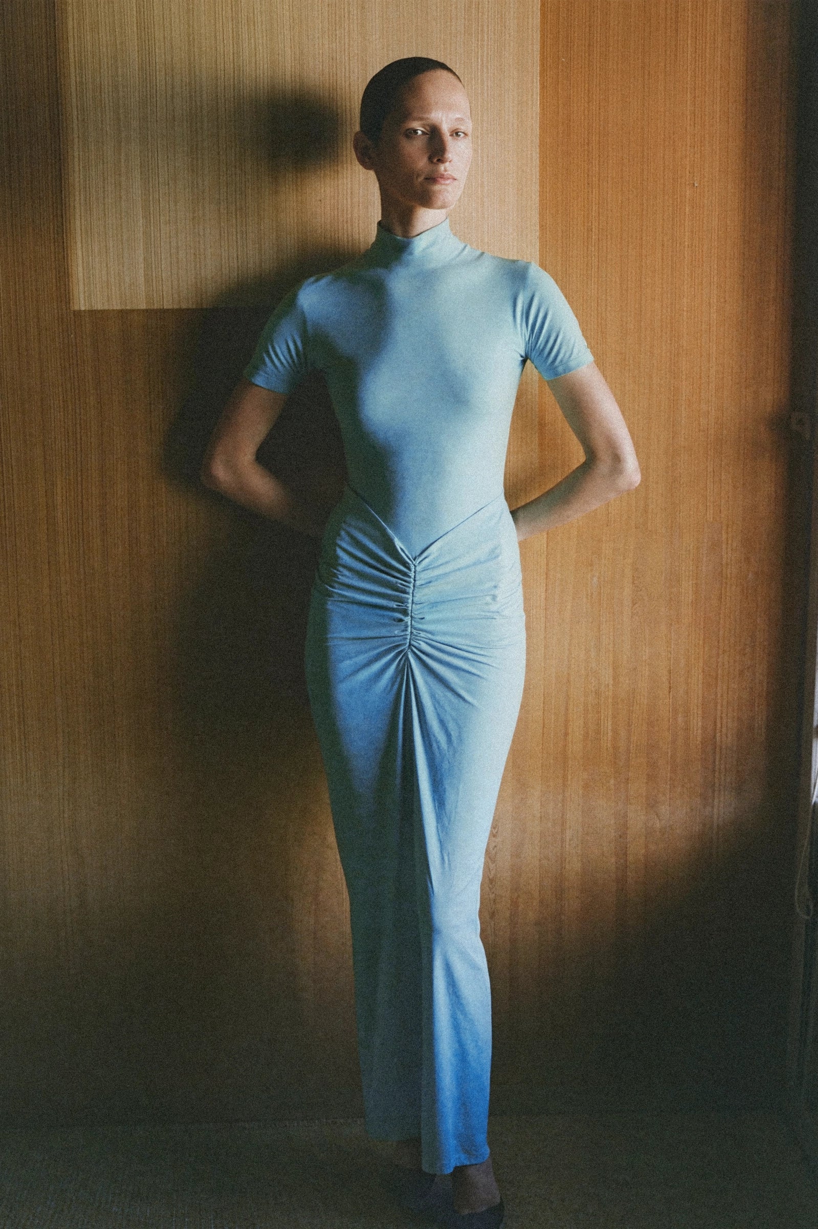 Front view of a cyan draped jersey maxi dress with a high neckline, short sleeves, and prominent central ruching.