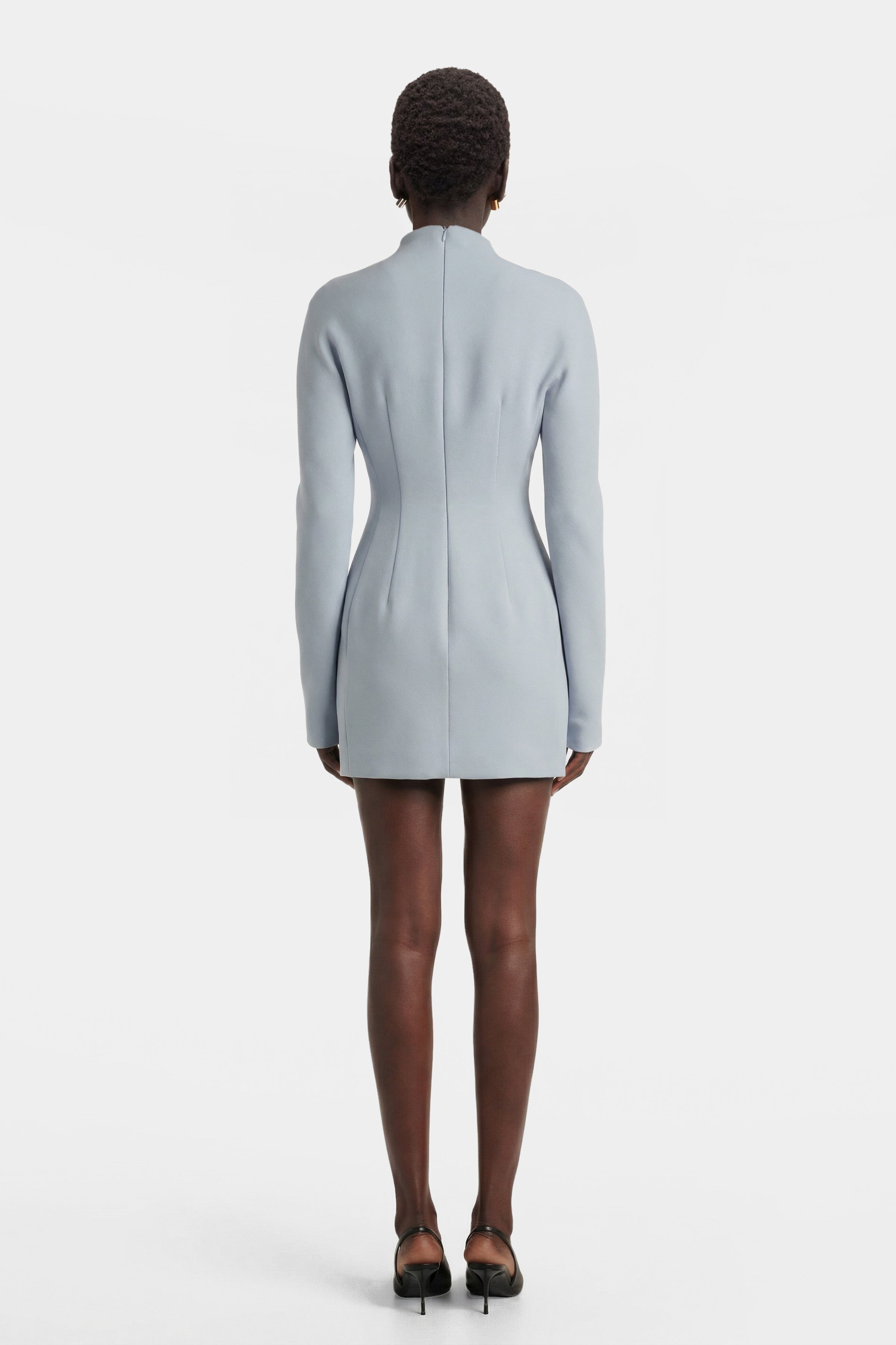Back view of a tailored light blue mini dress showing the invisible zipper closure, vertical seam detailing, and structured waistline.