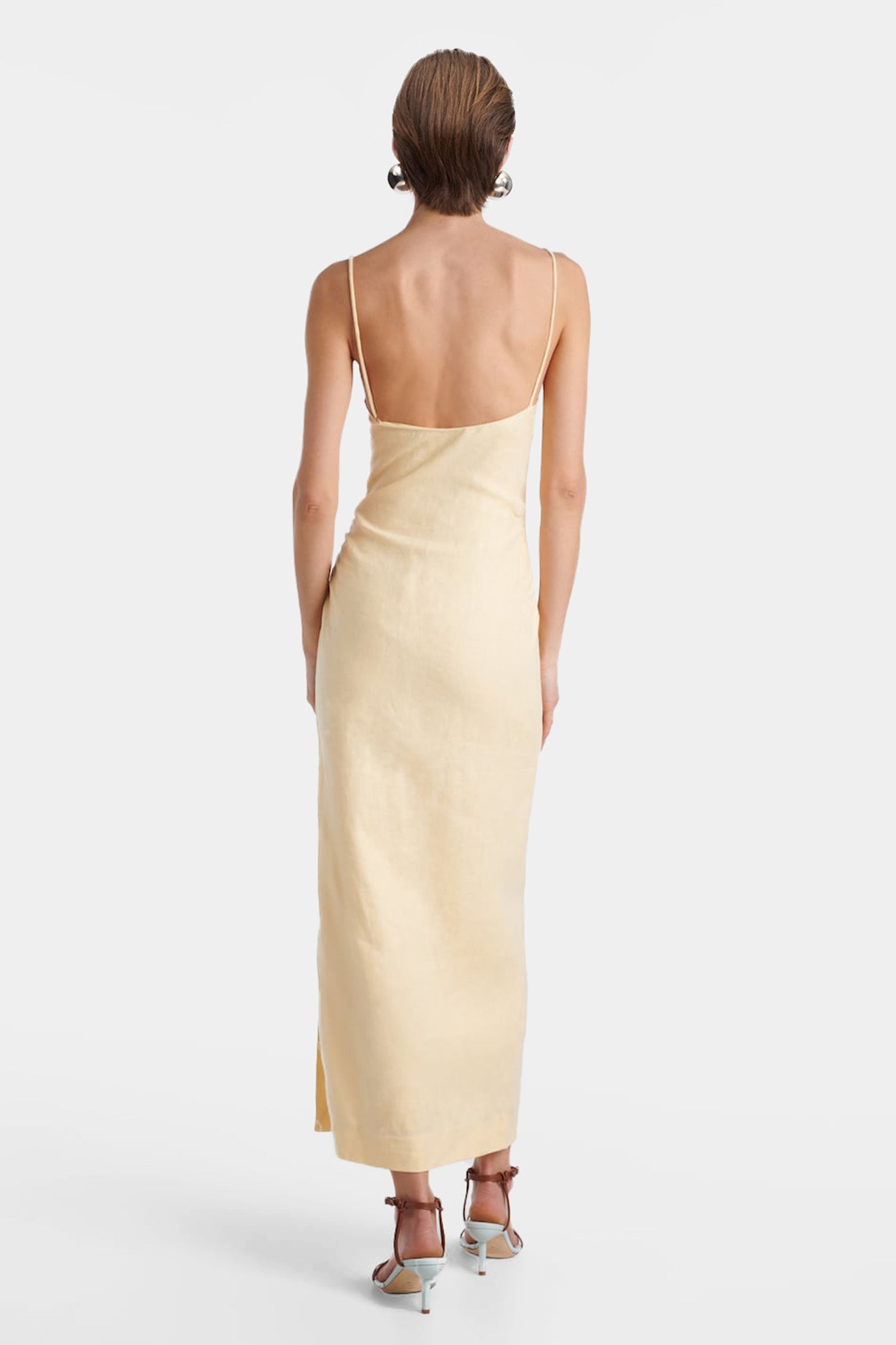 Back view of the yellow linen midi slip dress on a model, showing the delicate spaghetti straps and the smooth fit.