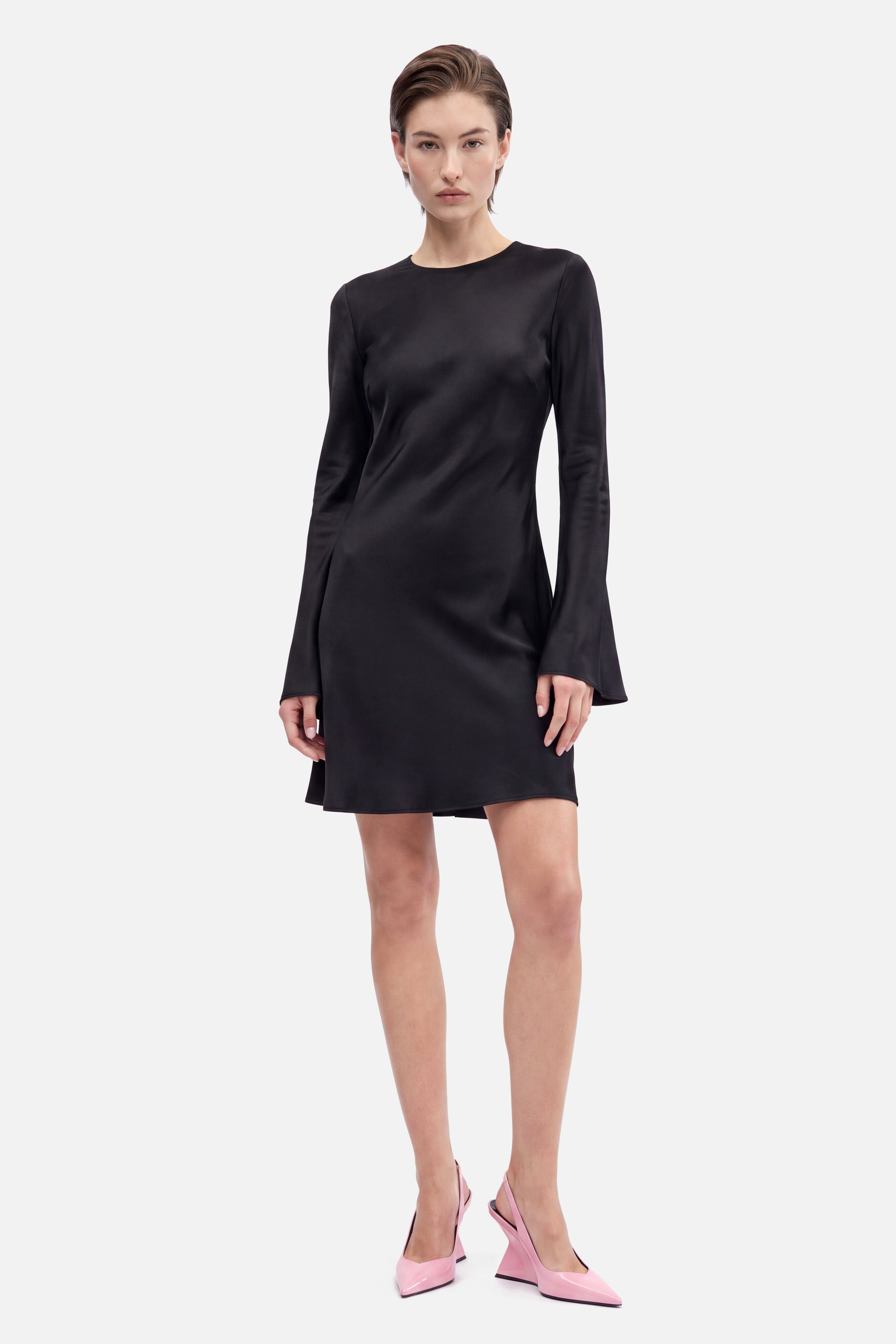 Front view of black satin dress with flare sleeves, model standing.