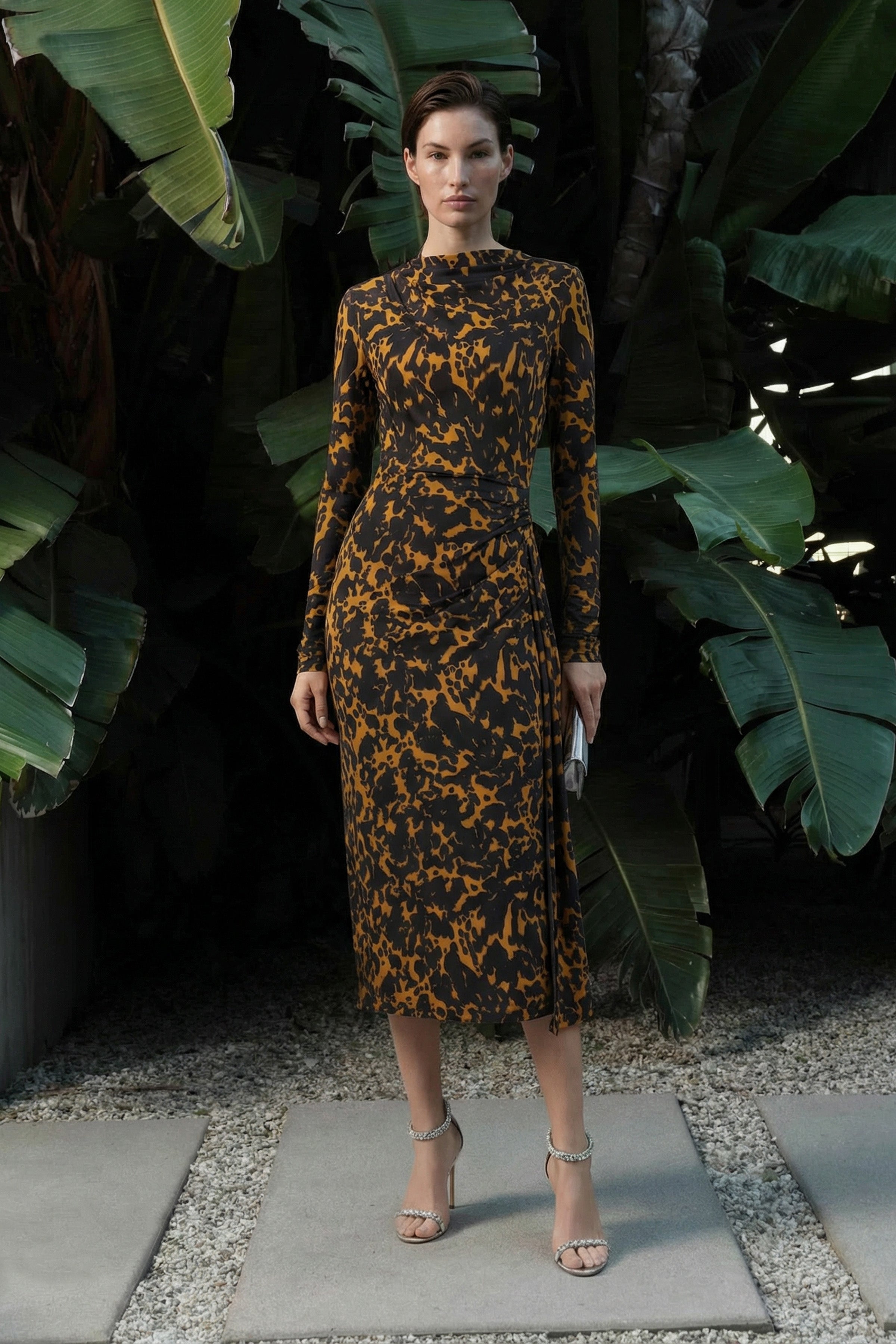 Fashion model posing outdoors in a long-sleeved abstract animal print midi dress with side ruching and a leg slit.