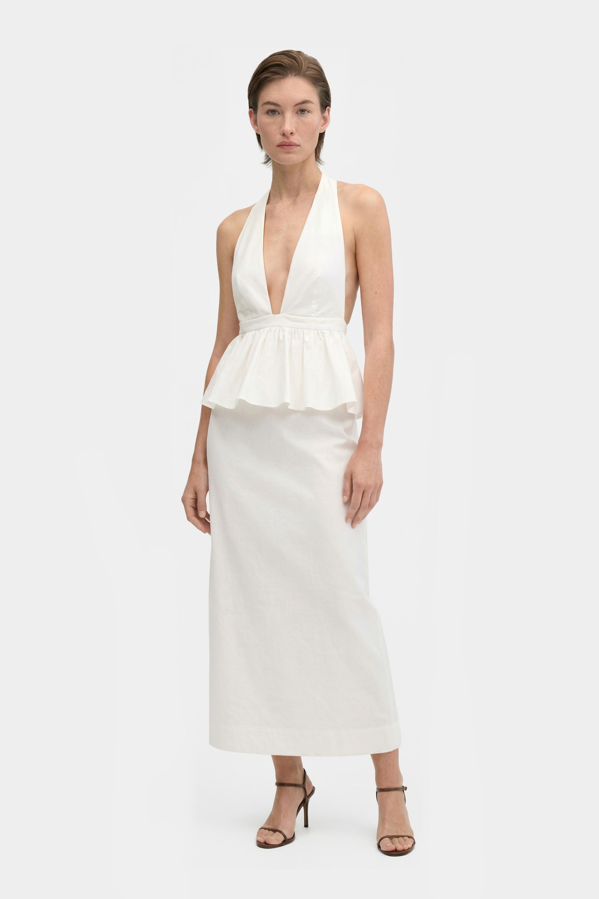 White halter peplum dress, front view, deep neckline, mid-length, model standing.