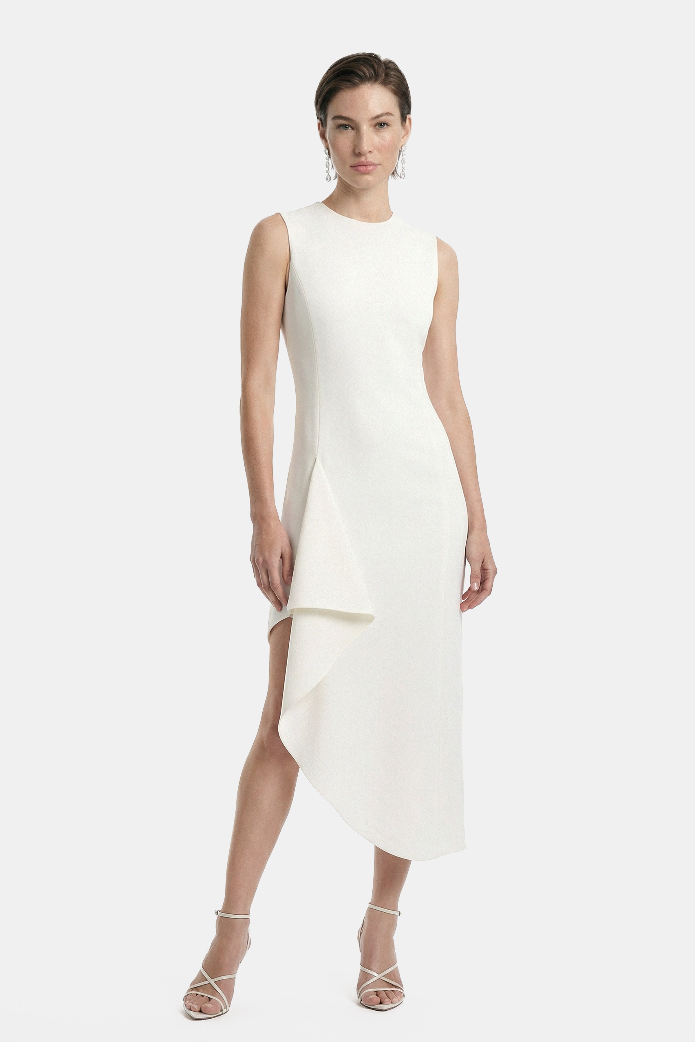 Model wearing asymmetrical white dress, sleeveless, front view, with draped side detail.