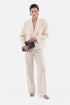 Ivory tailored suit, front view, model holding black clutch, wearing gold earrings.