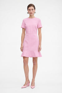 Model in pink flounce hem dress, front view, standing, wearing matching pink heels.