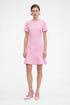 Model in pink flounce hem dress, front view, standing, wearing matching pink heels.