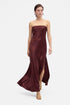 Model wearing burgundy strapless gown, thigh-high slit, flowing front view, gold sandals.