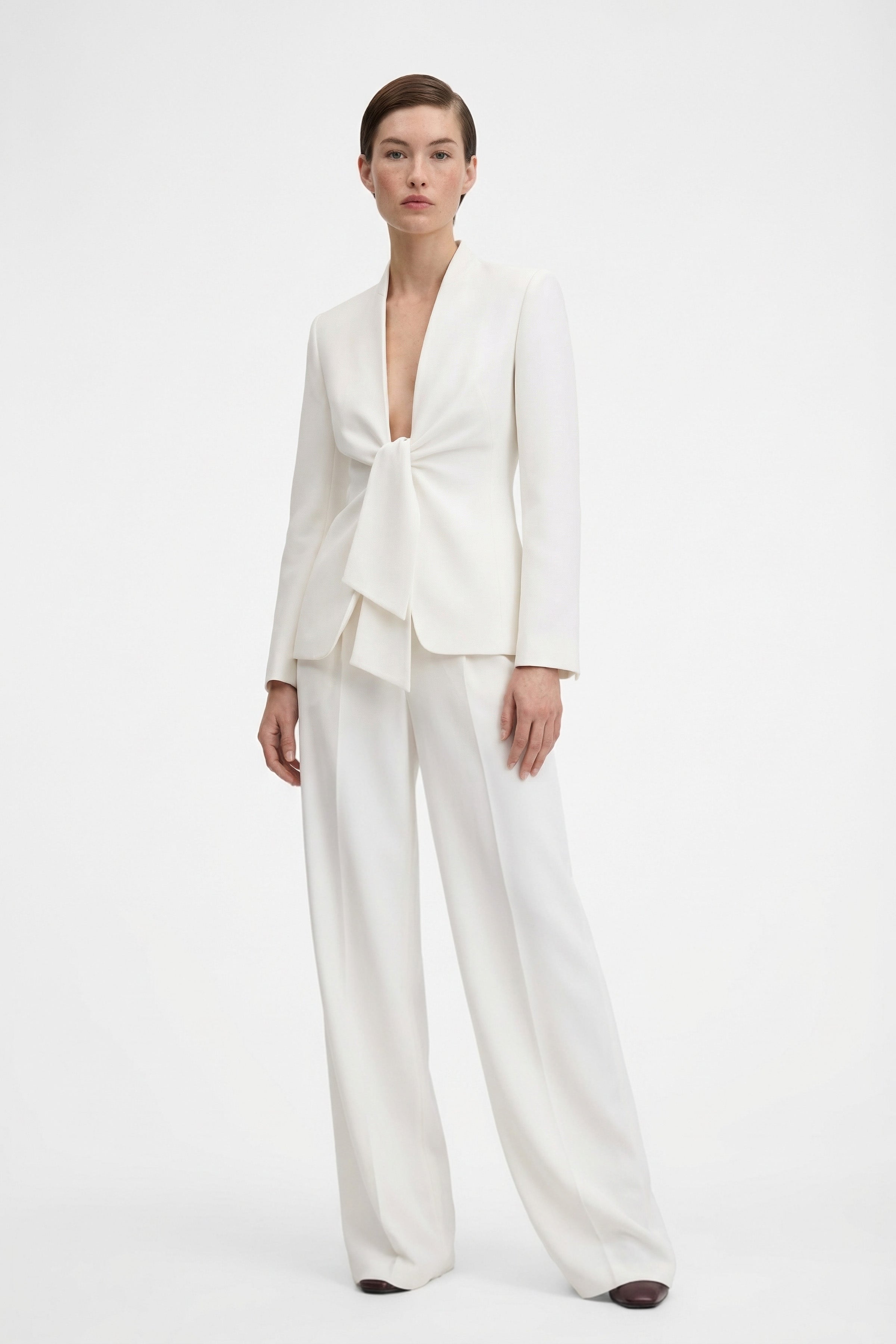 Model wearing ivory tie-front suit, front view, long sleeves, wide-leg pants.