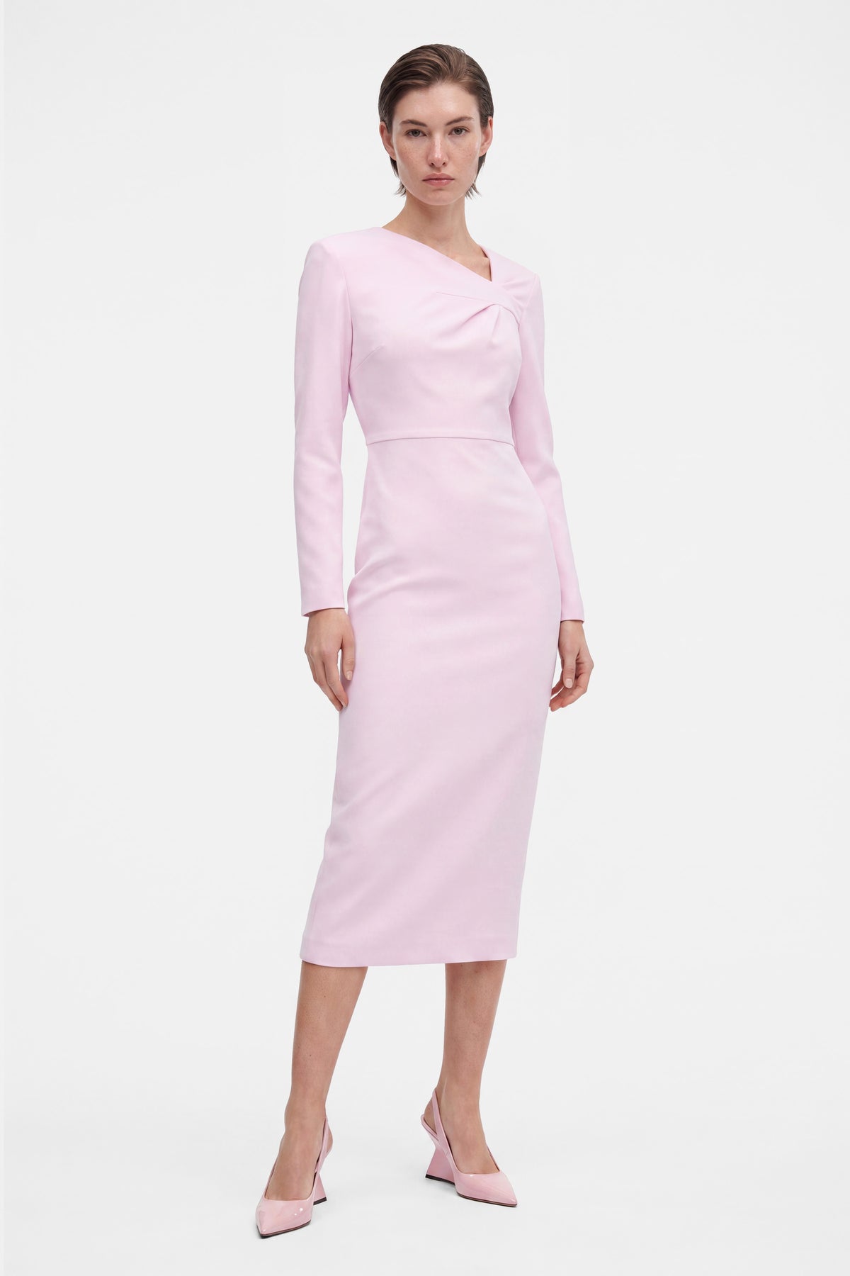 Model wearing soft pink asymmetrical dress, front view, long sleeves, knee-length.
