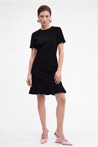 Front view of black ruffle hem dress on model with pink heels.