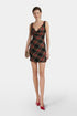 Model wearing a plaid mini dress, draped neckline, red shoes, front view.