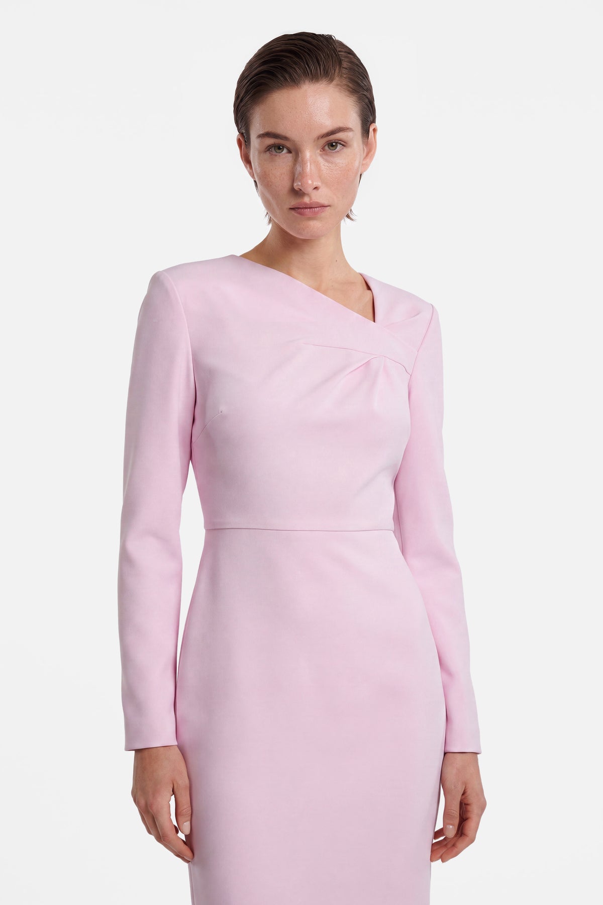 Front view of soft pink asymmetrical dress with long sleeves and fitted silhouette.