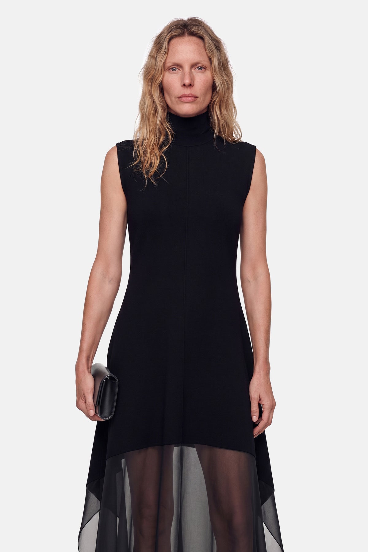 Model wearing black sleeveless sheer overlay dress, front view with clutch.