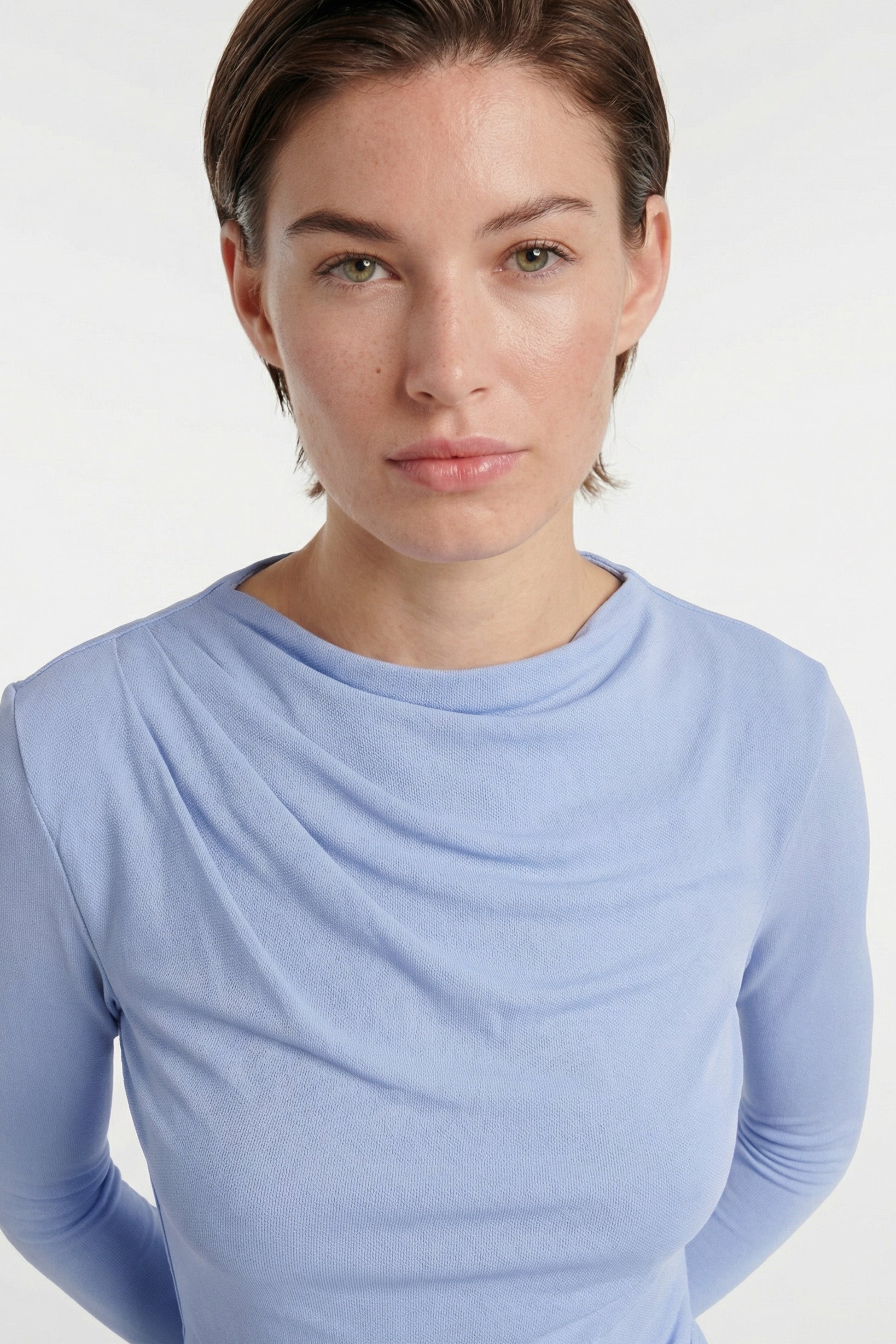 Model wearing sky blue draped midi dress, close-up of neckline and shoulders.