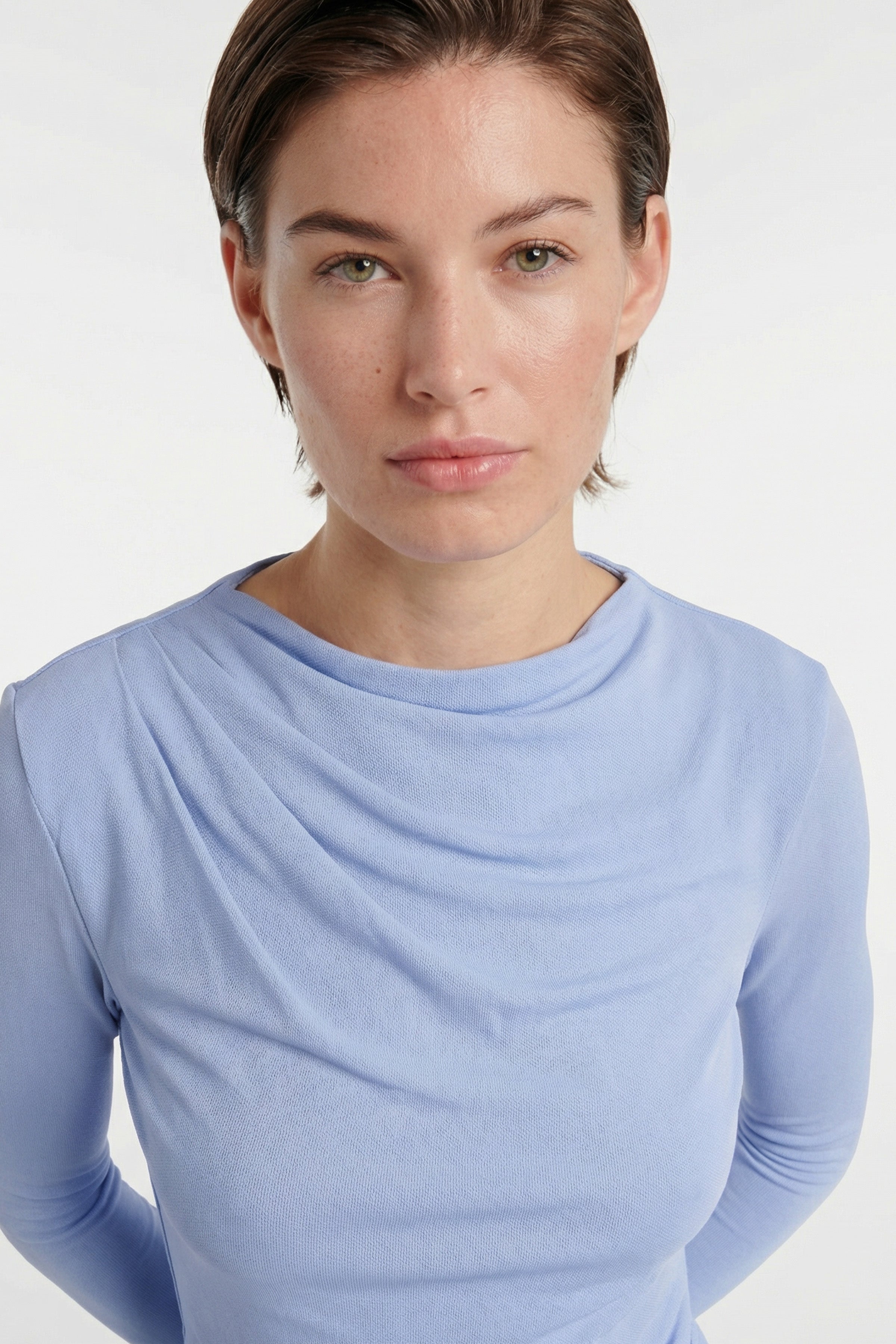 Model wearing sky blue draped midi dress, close-up of neckline and shoulders.