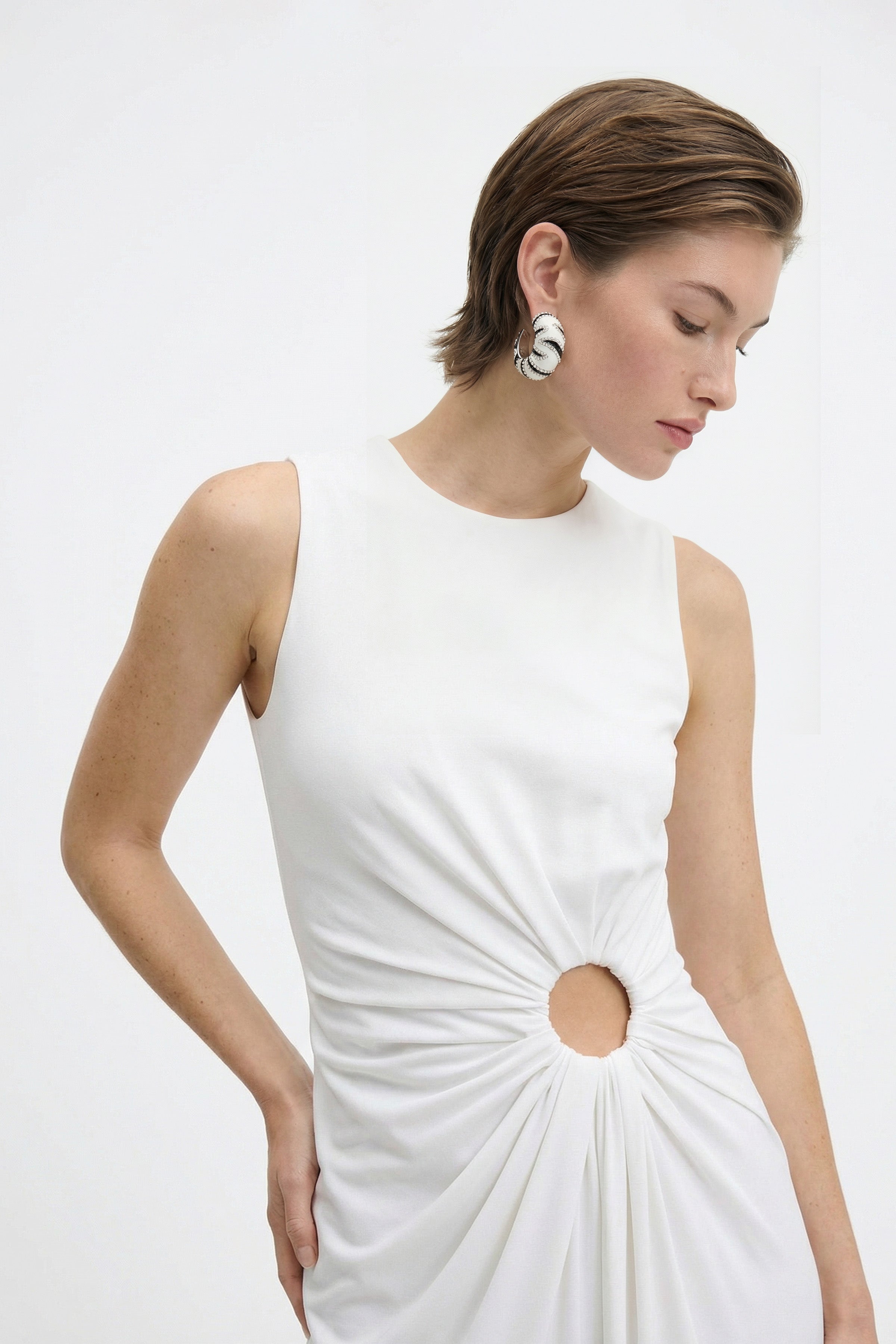 Close-up of white gown with circular cut-out detail and sleeveless design.