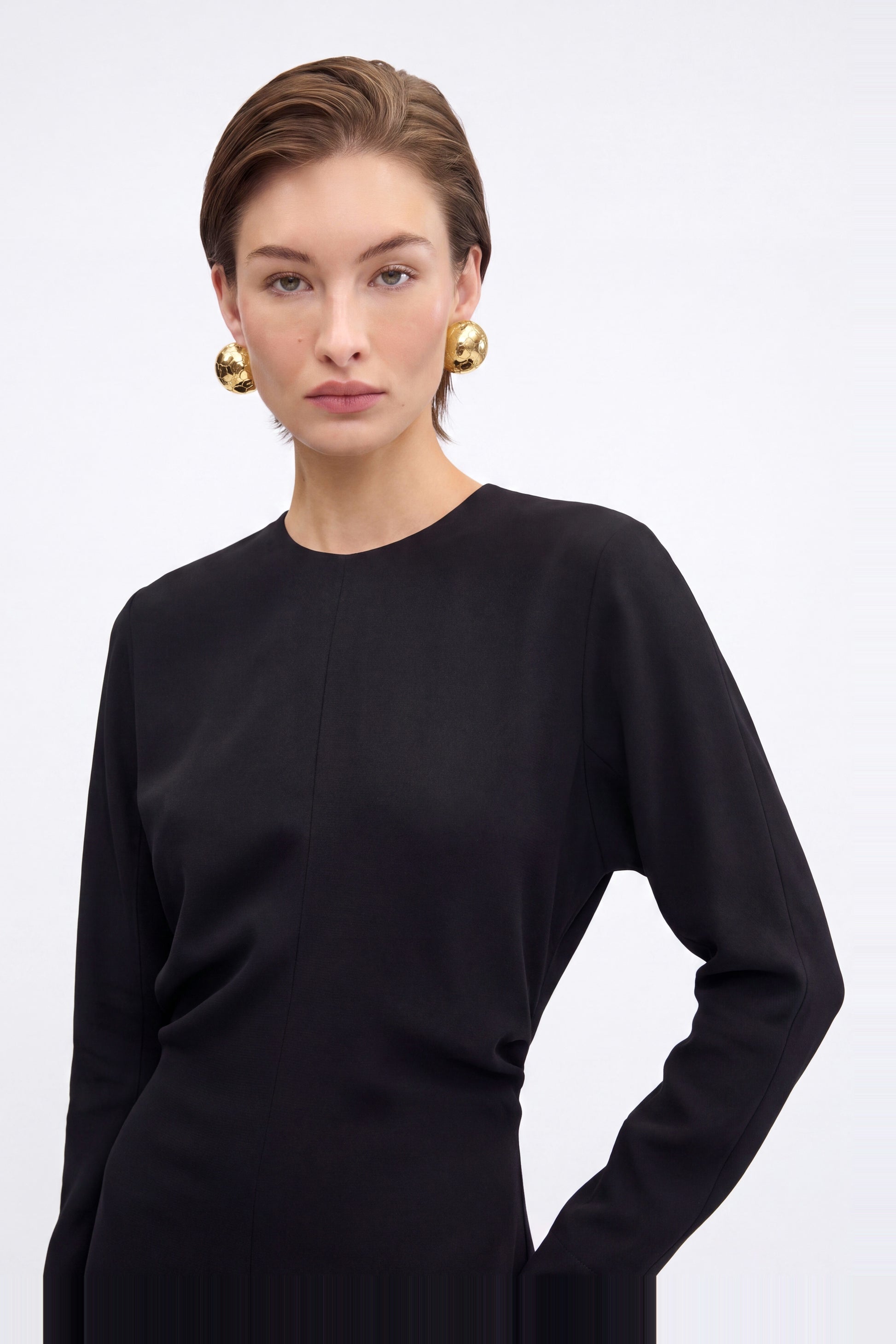 Front view of black long sleeve maxi dress, model wearing large gold earrings.
