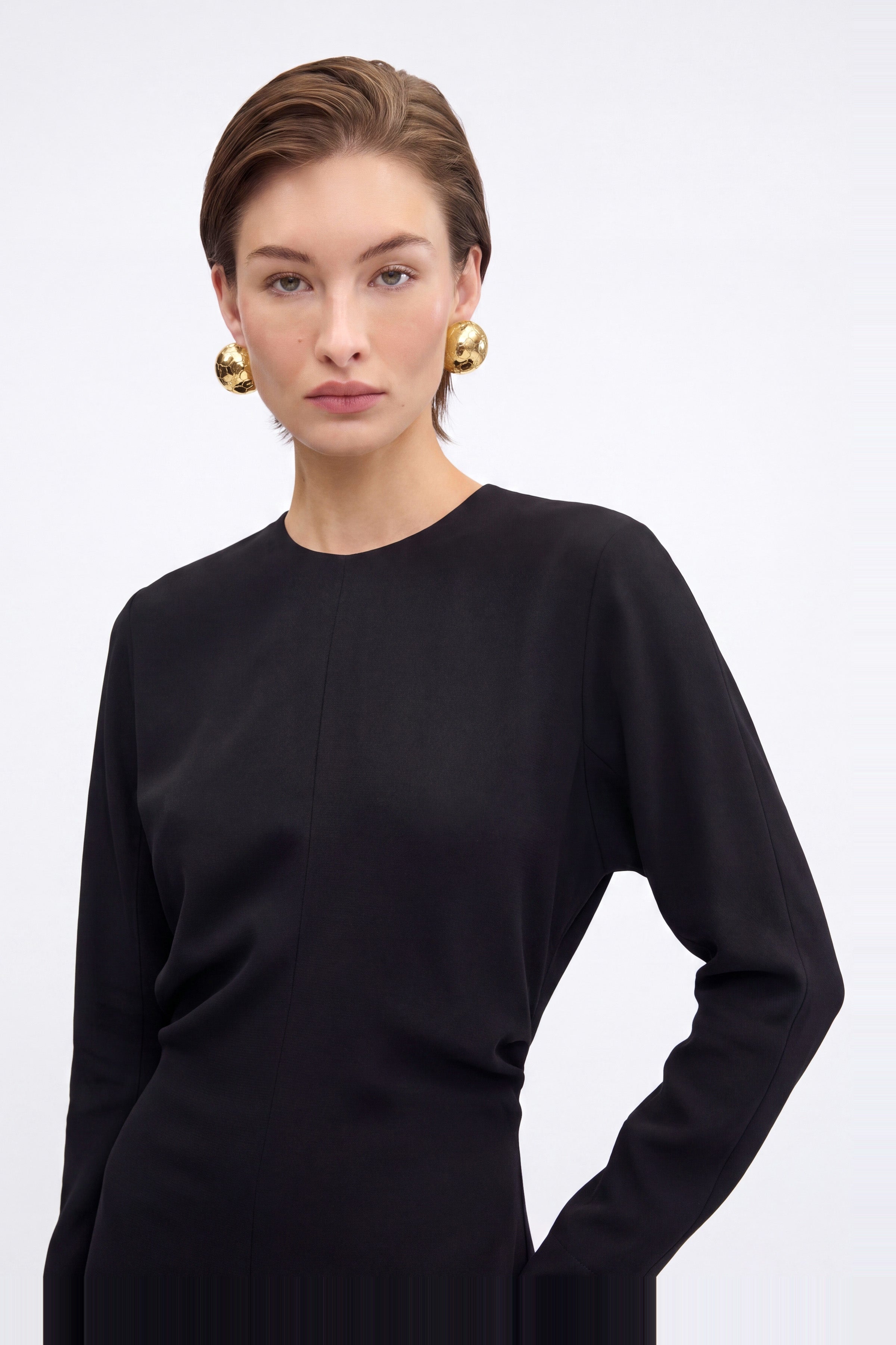 Front view of black long sleeve maxi dress, model wearing large gold earrings.