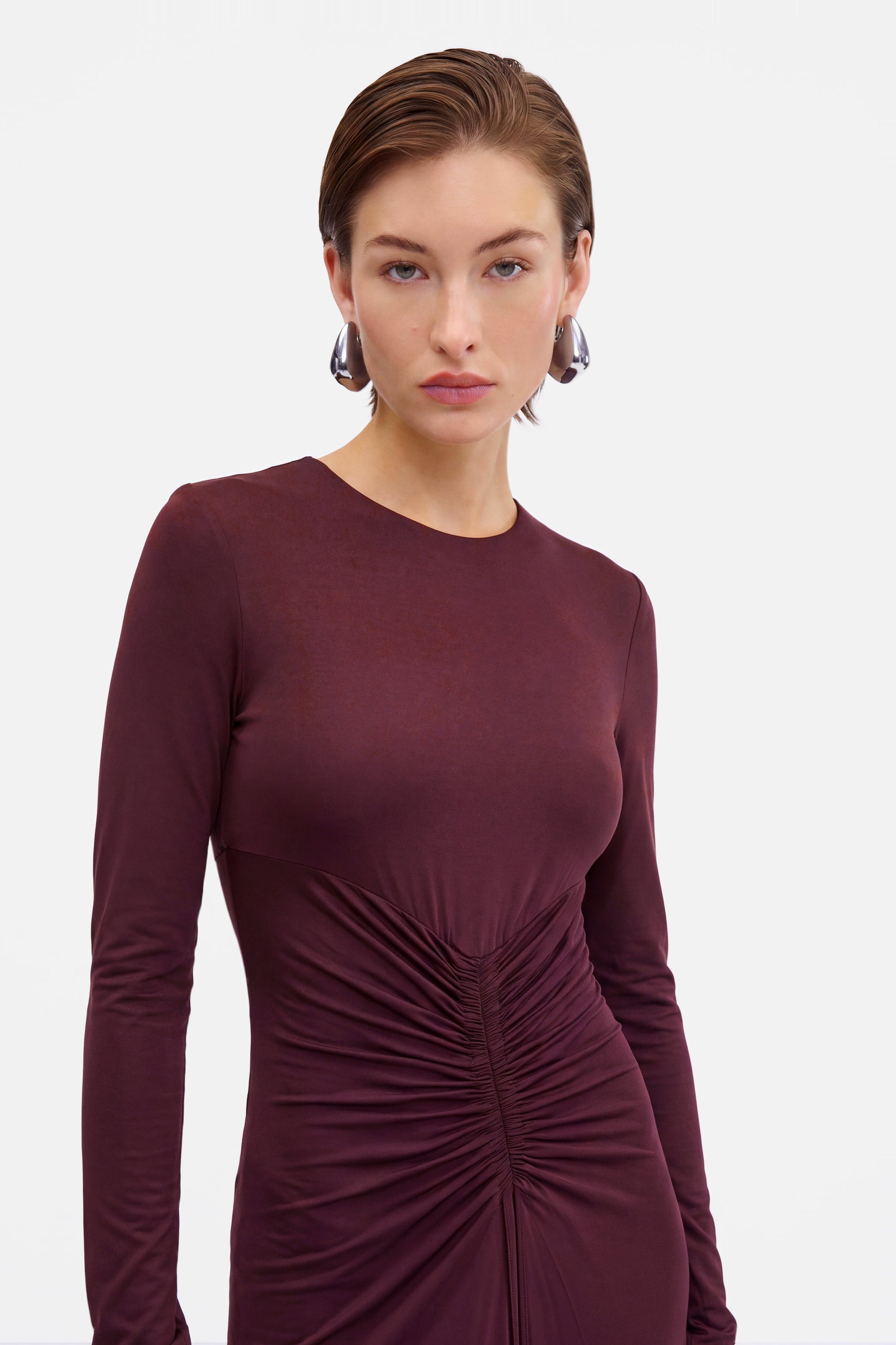 Front view of burgundy ruched long sleeve dress on model, close-up detail.