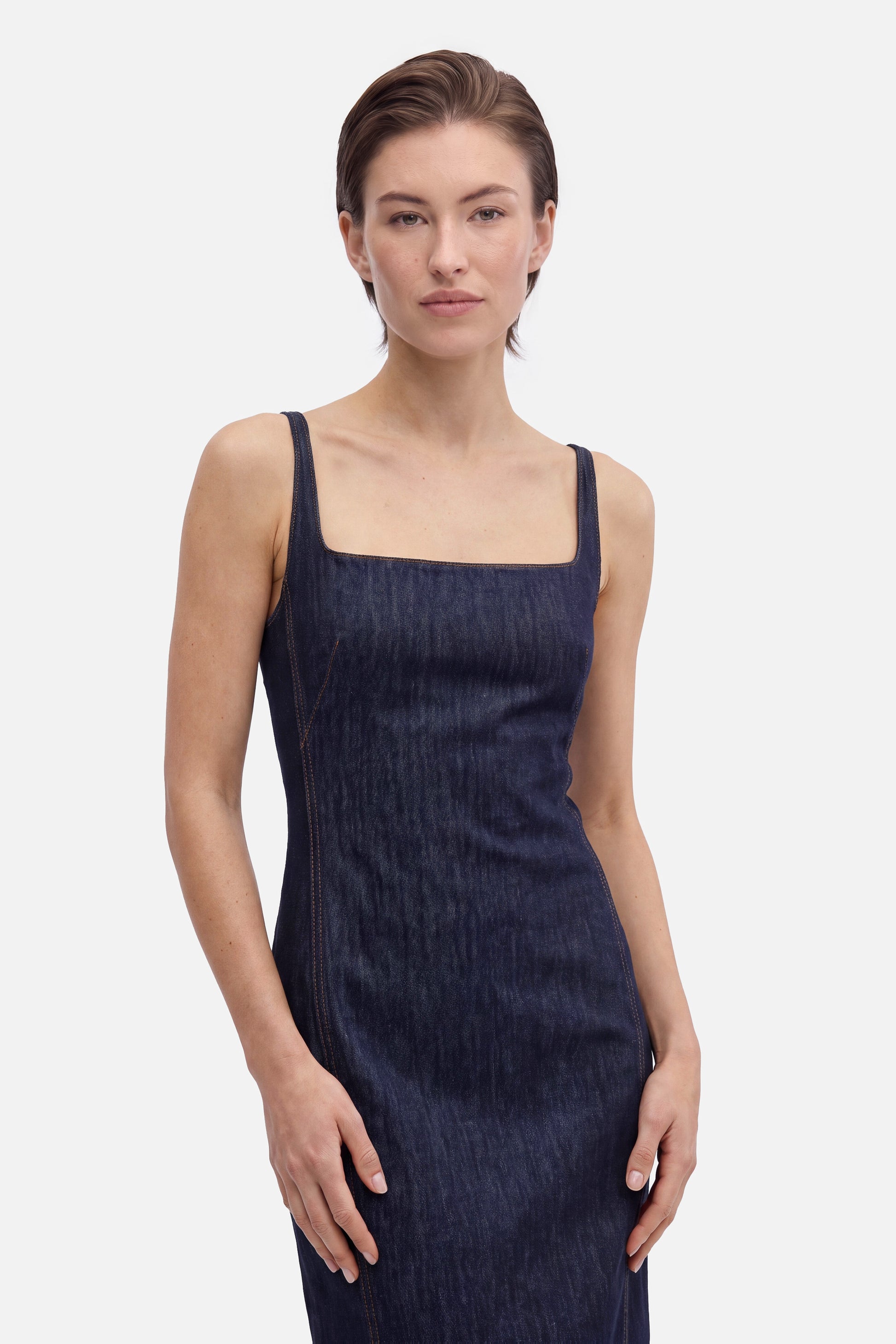 Front view of model in square neck denim midi dress, neutral expression.