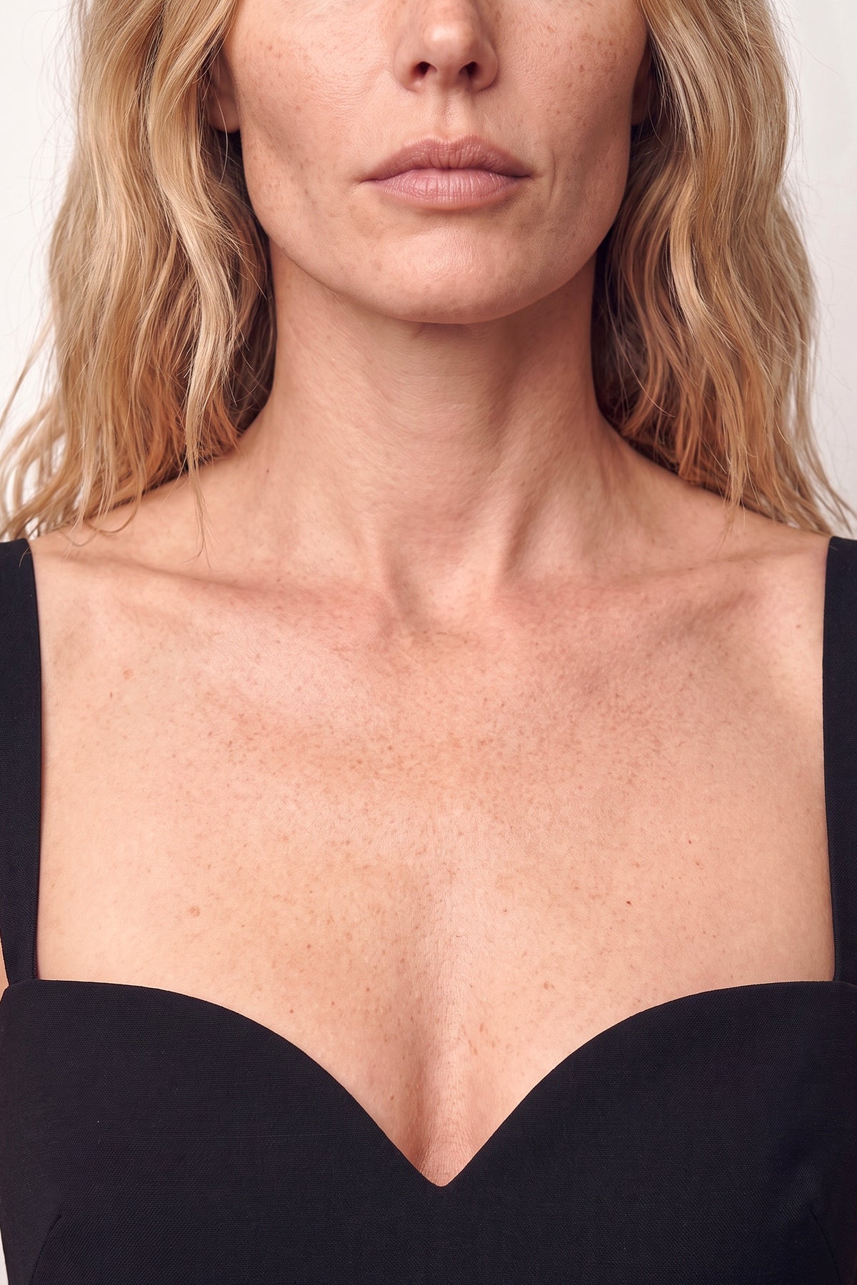 Close-up of black sweetheart neckline dress on model, showing detailing and fit.