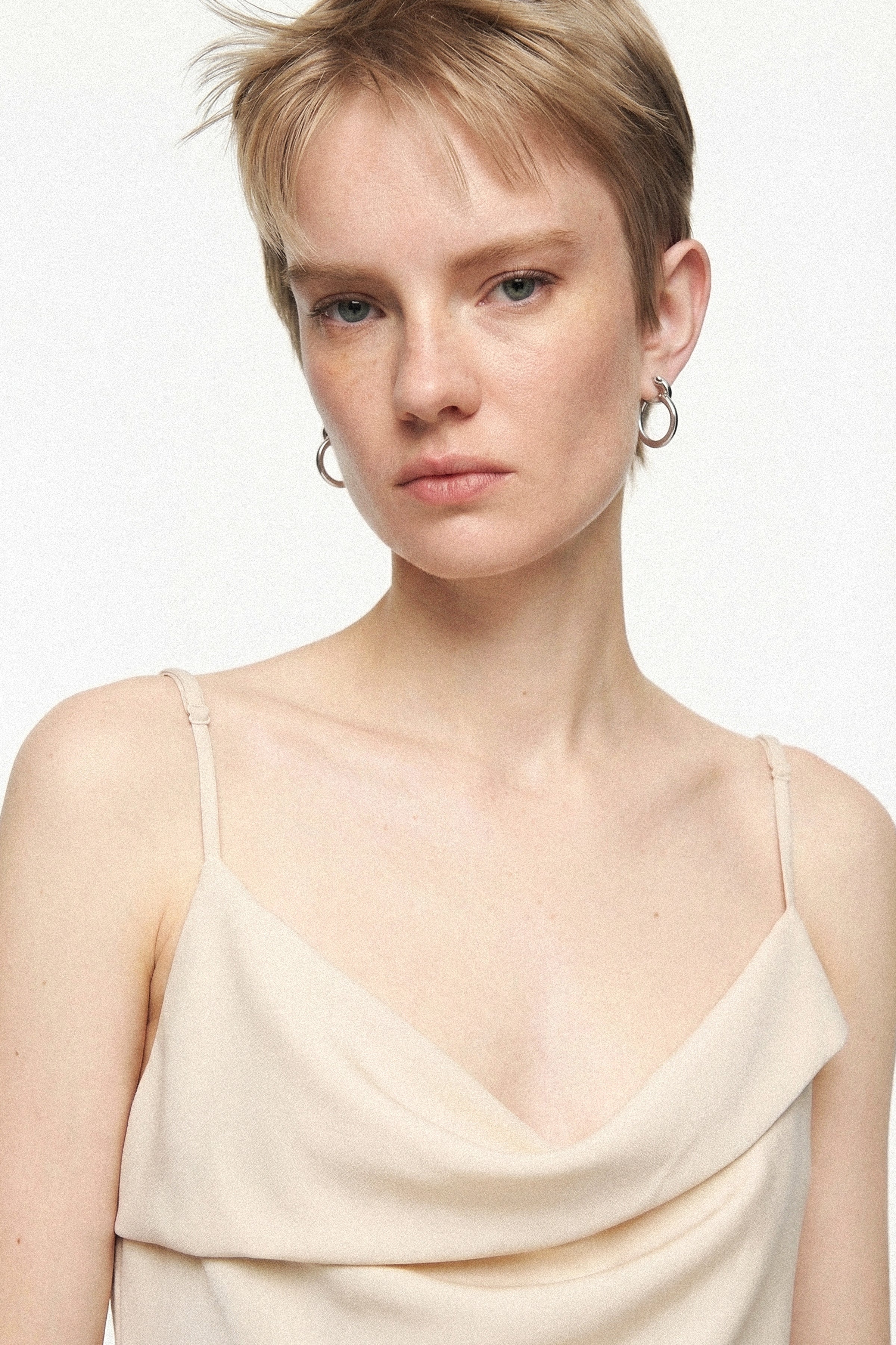 Front view of a model wearing a beige silk cowl neck slip dress.