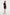Back view of model in black ruffle shoulder mini dress, holding white clutch.