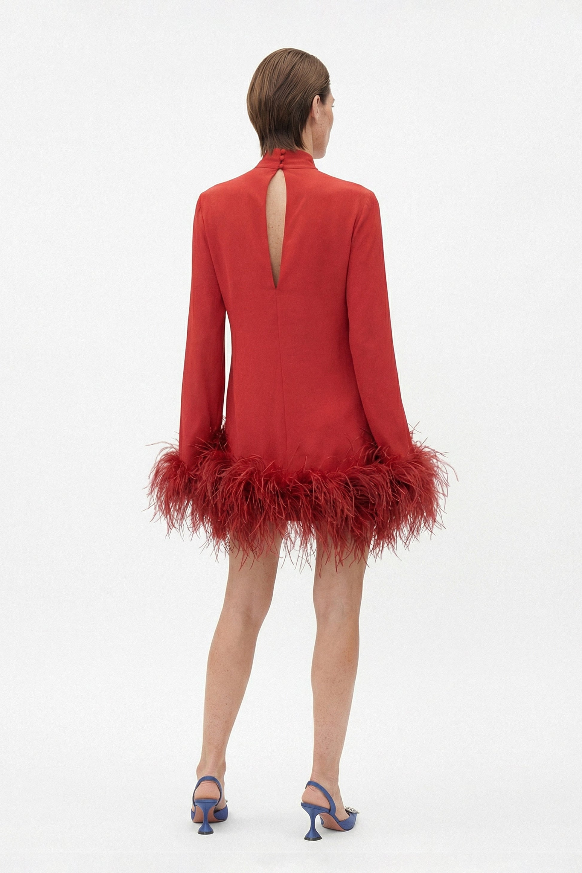Rear view of model wearing a red dress with feather trim and back keyhole.