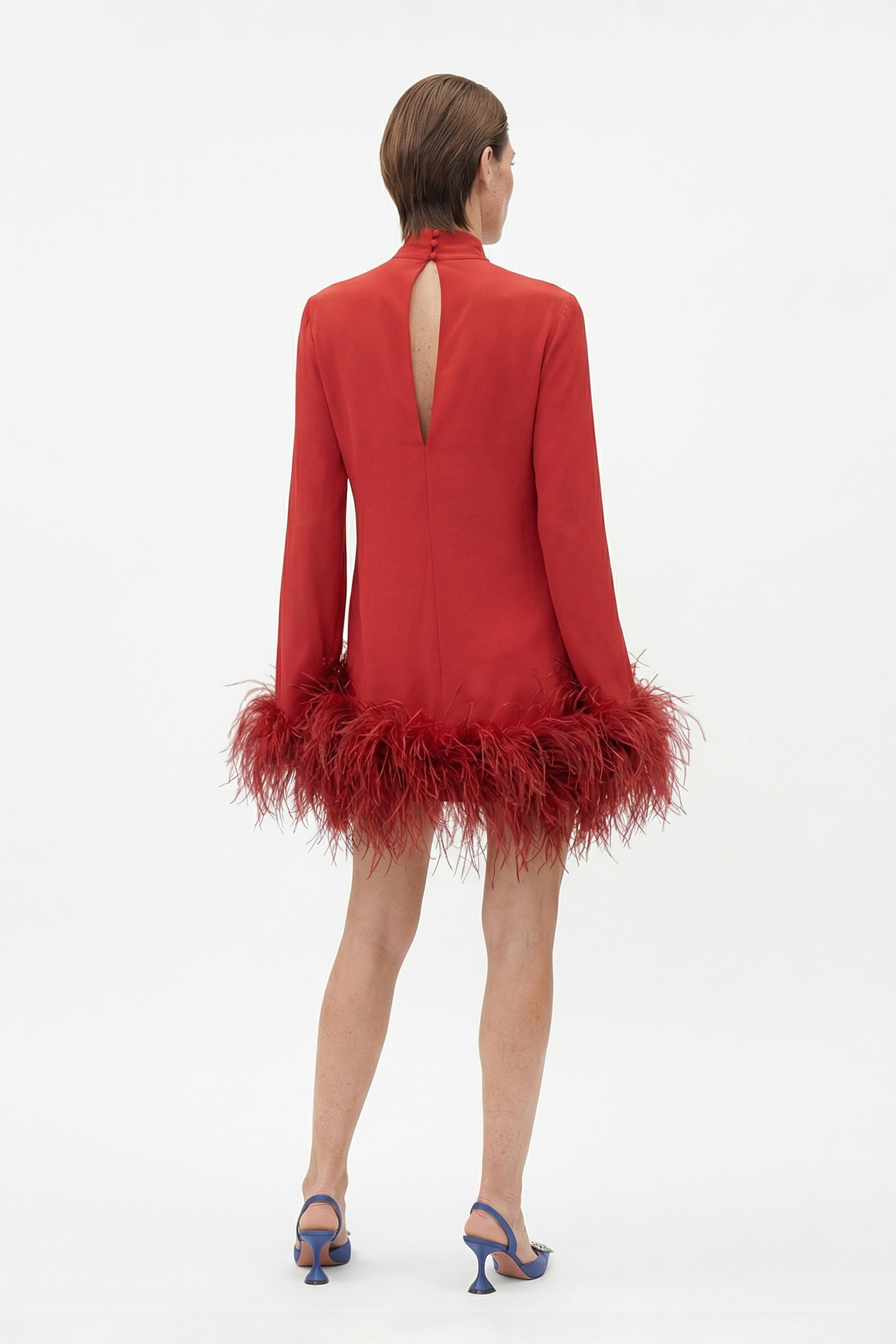 Rear view of model wearing a red dress with feather trim and back keyhole.