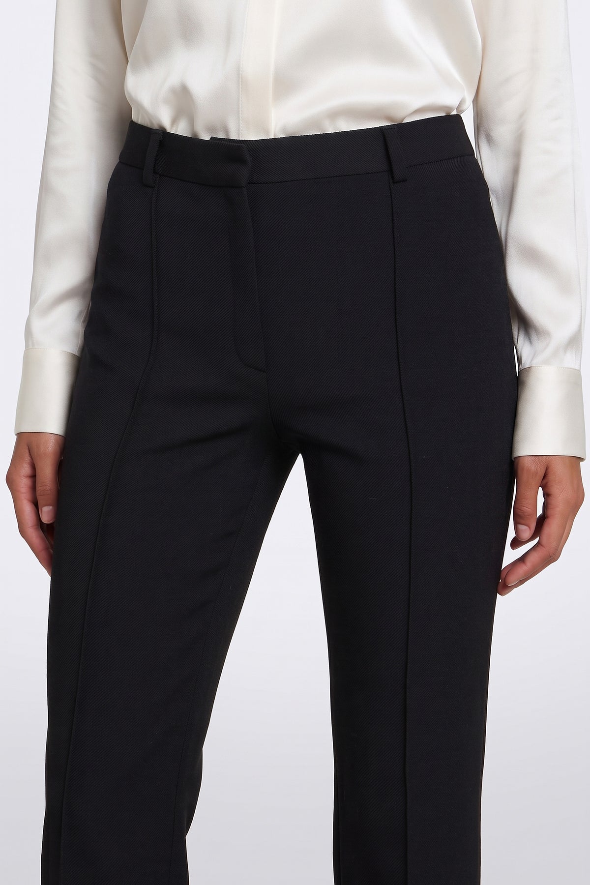 Front view of tailored black suit pants with white shirt, close-up detail.