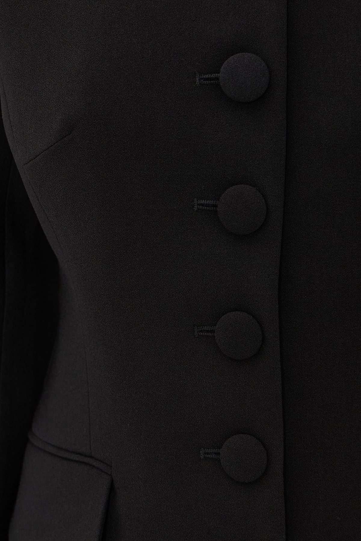 Close-up of structured black blazer with large round buttons, showcasing texture and details.