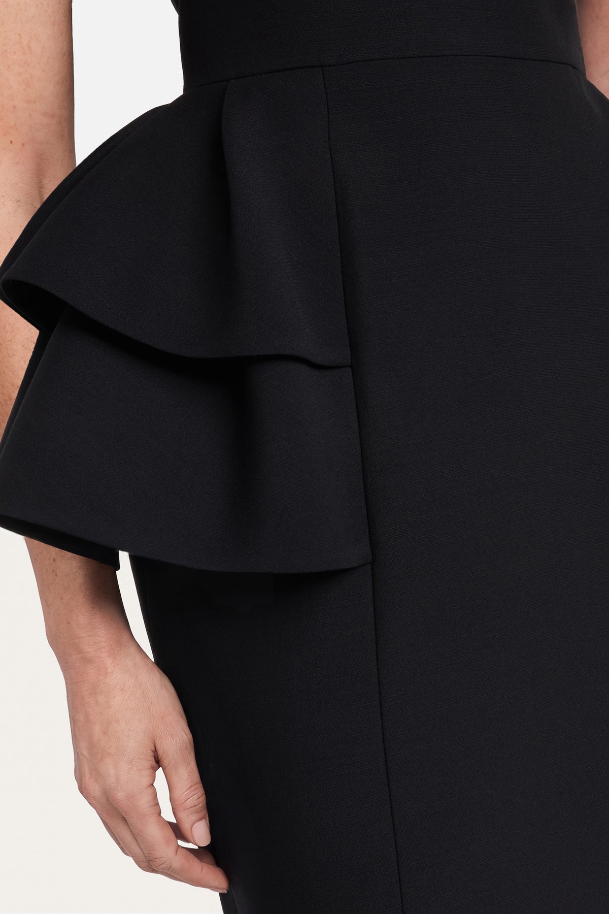 Close-up of black dress with layered ruffle detail at the waist.