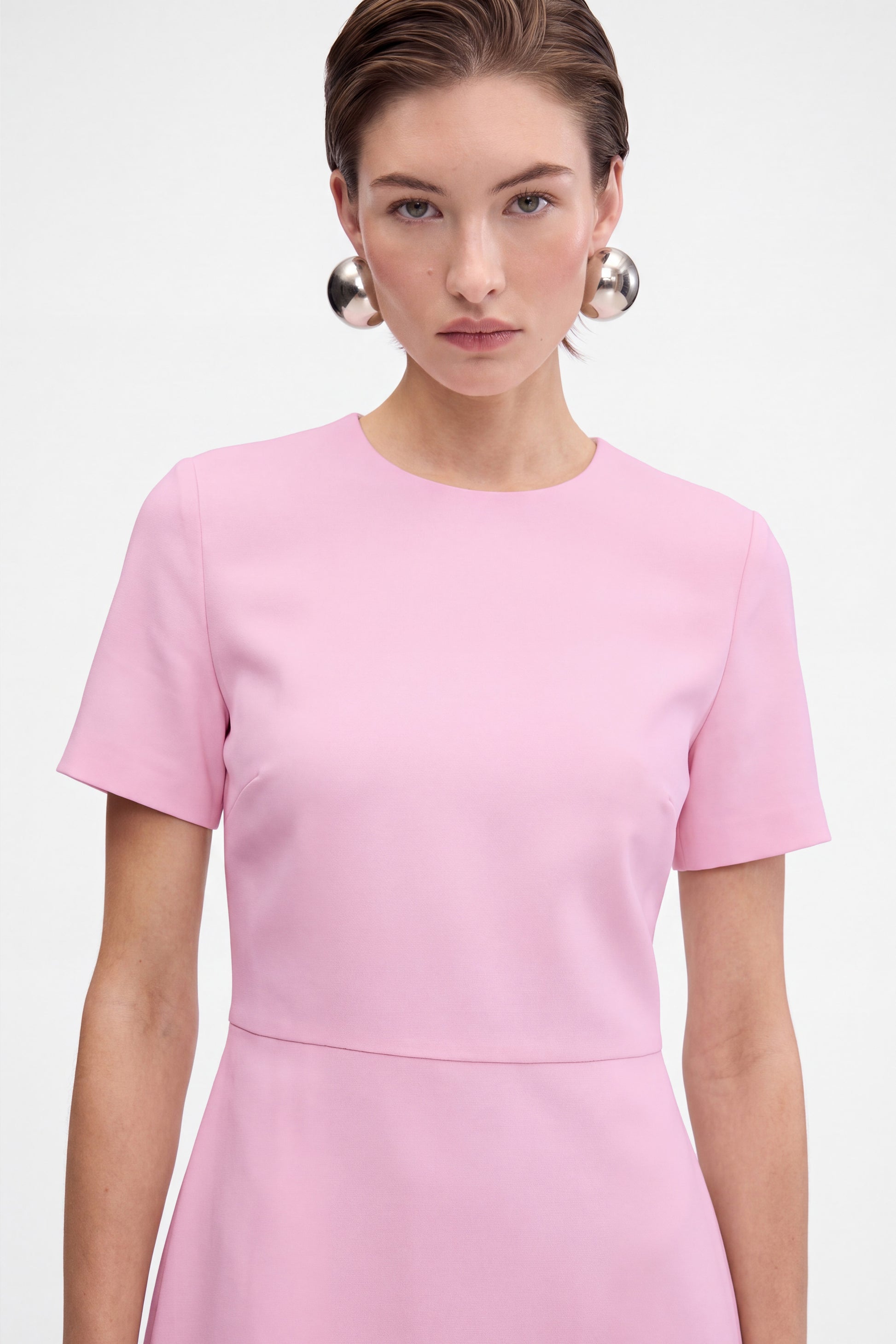 Front view of pink flounce hem dress, crew neck, short sleeves, on model.