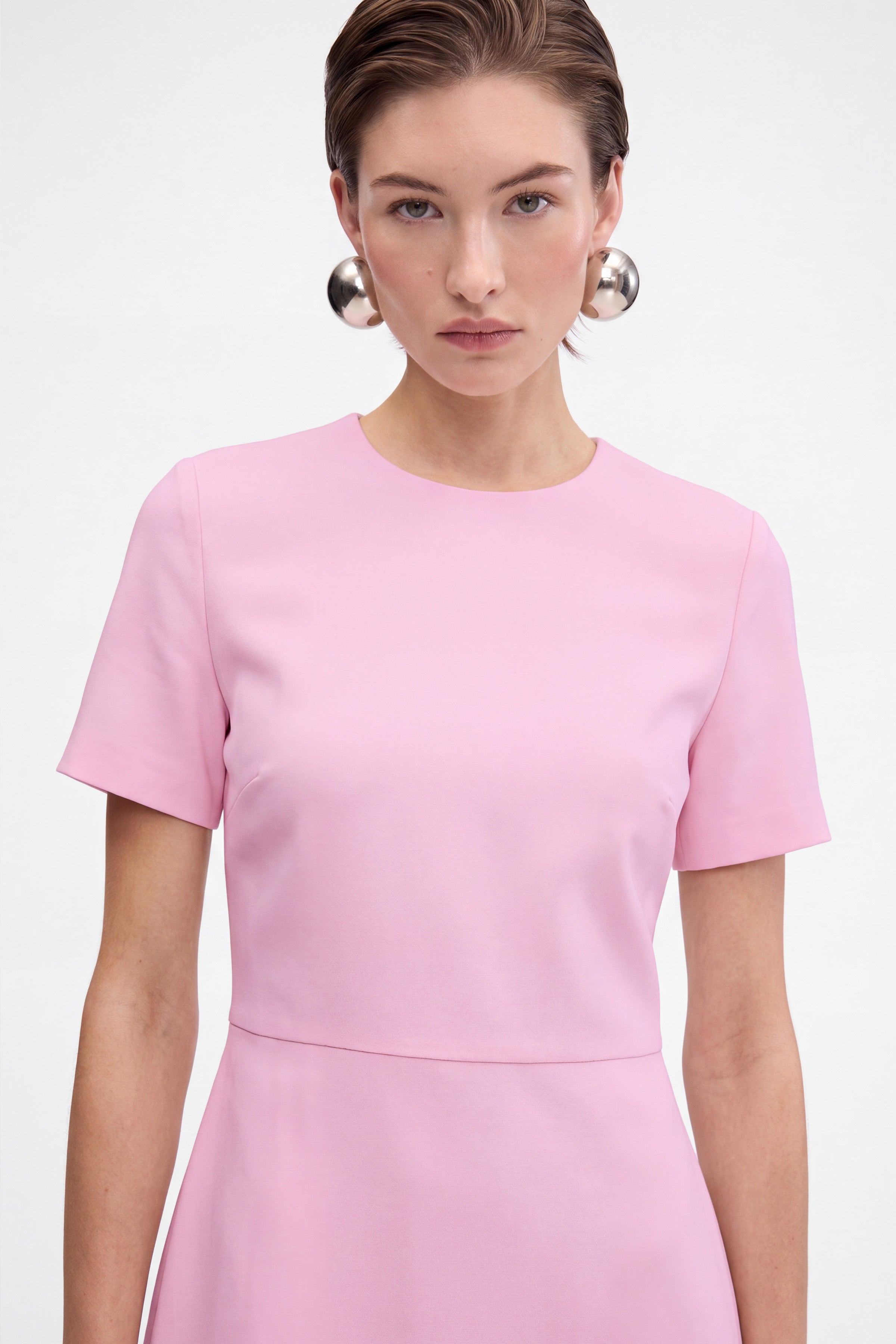 Front view of pink flounce hem dress, crew neck, short sleeves, on model.