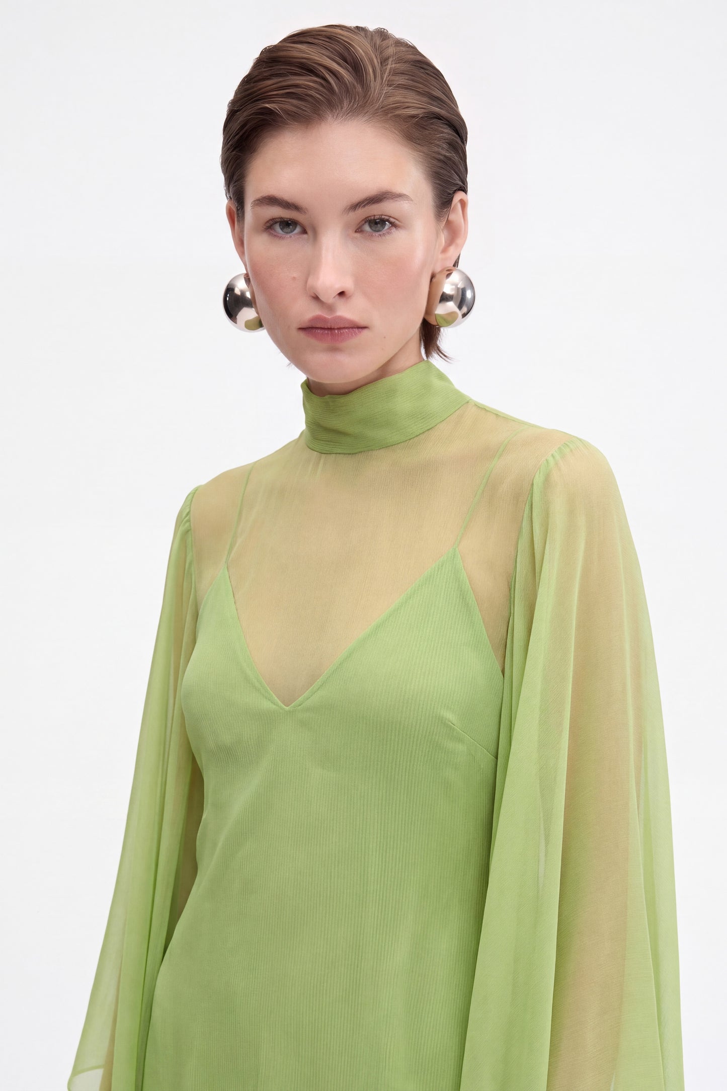Close-up of sheer lime green chiffon cape overlay and V-neck slip lining, high neck detail