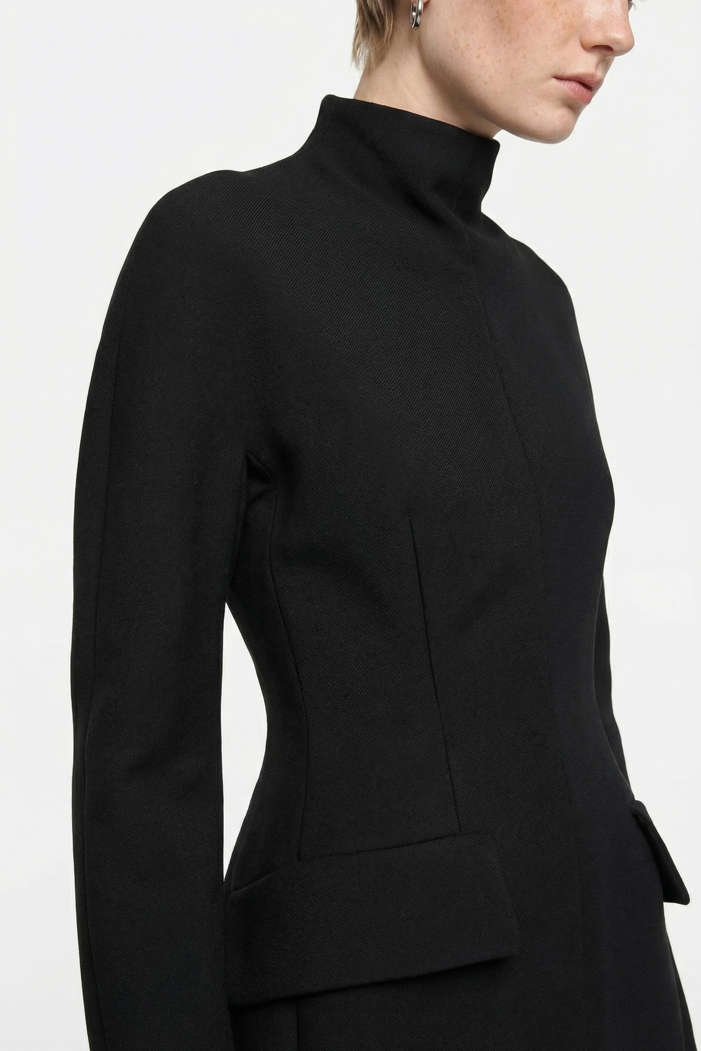 Close-up of black tailored mini dress with high neckline and structured detailing.