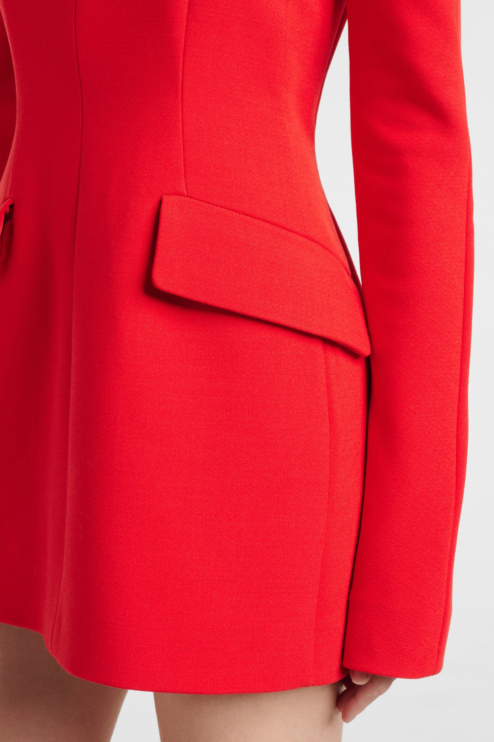 Close-up of a red structured mini dress with a pocket flap detail.